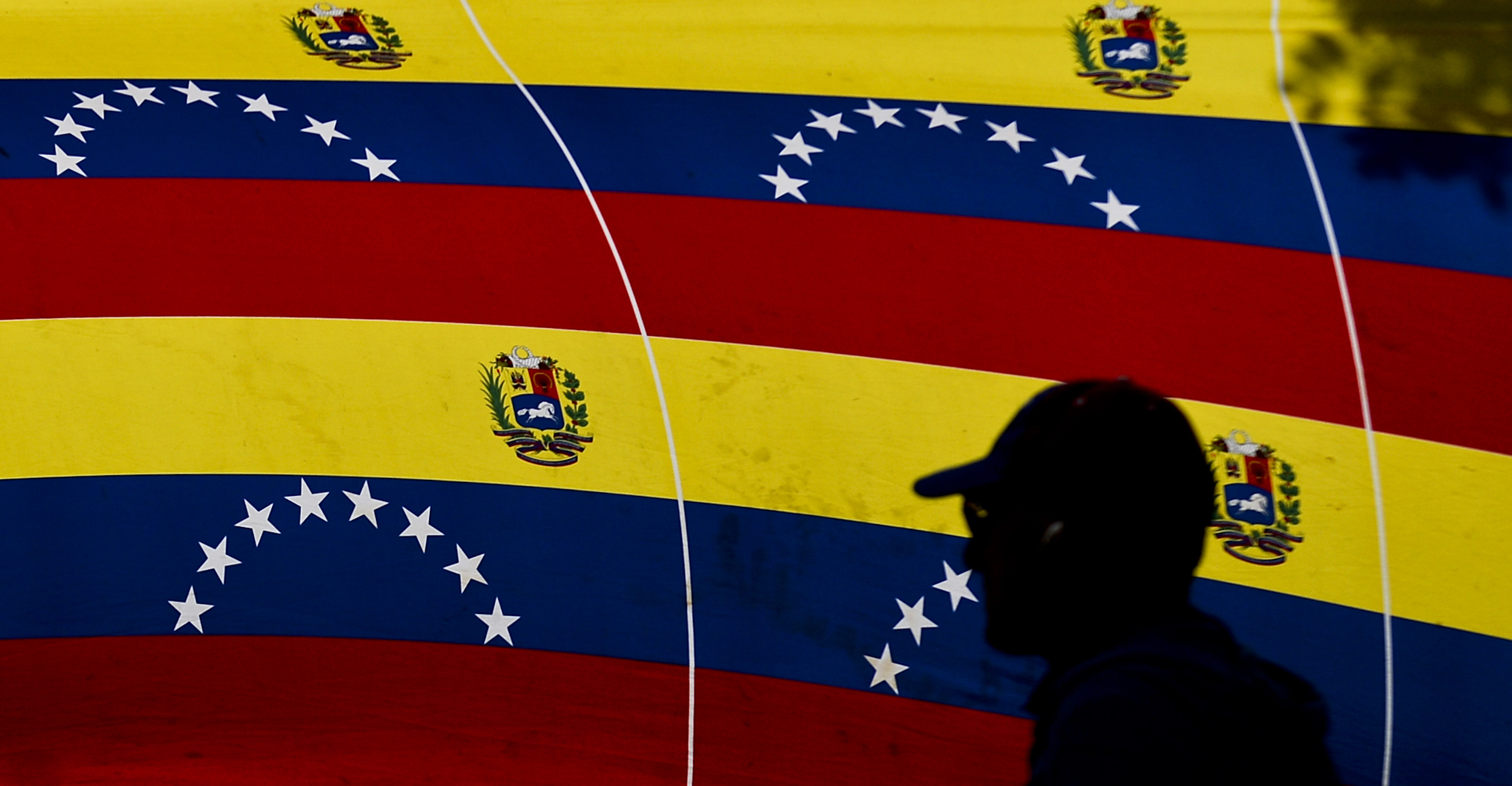 A man passes by national flags at a polling station during Venezuela's legislative election in Caracas on Dec. 6, 2015. (Luis Robayo—AFP/Getty Images)