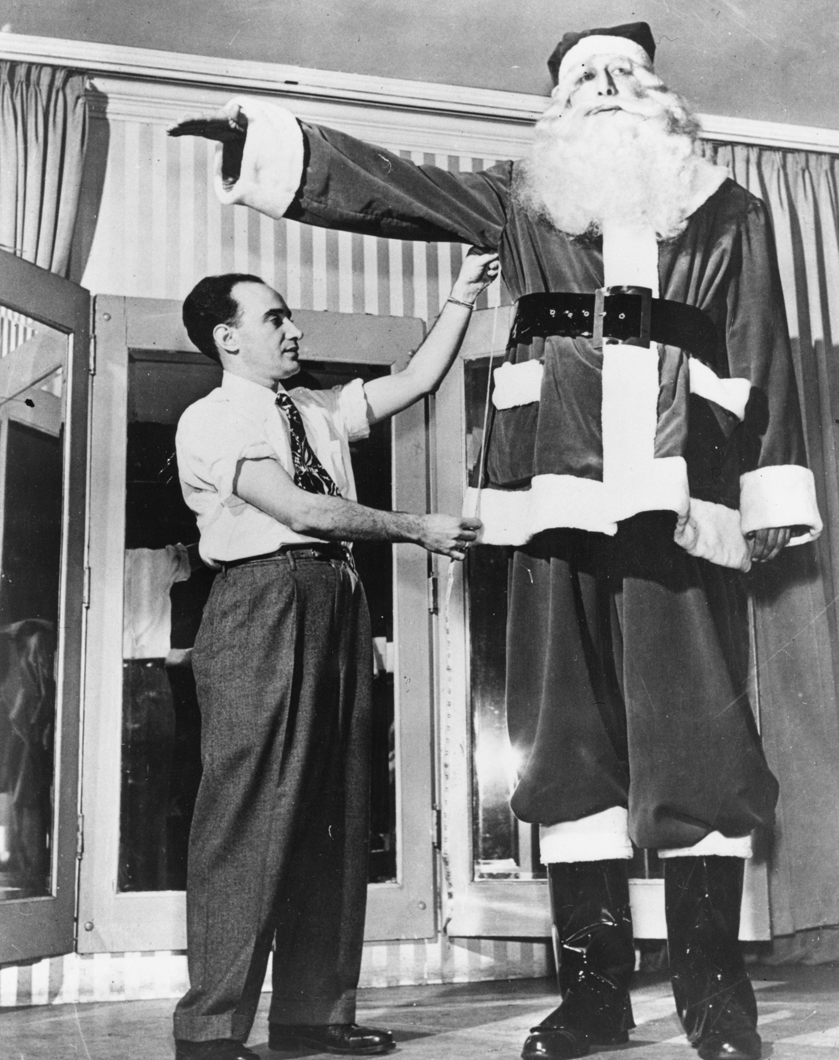 Claimed to be the biggest Santa Claus in the world, 7'8  Jacob Hudson Nacken is fitted for his costume by a tailor on arrival in New York from Germany.  December 1949.
