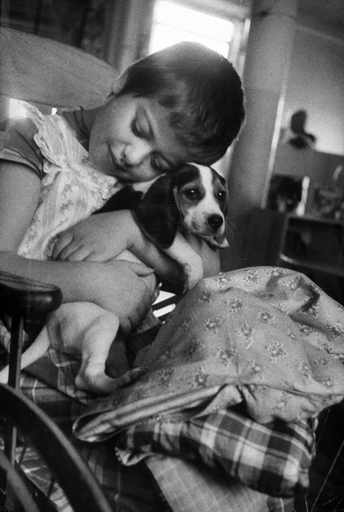 A child cuddling with a puppy as one of the hospital's methods of using therapy through animals, 1956.