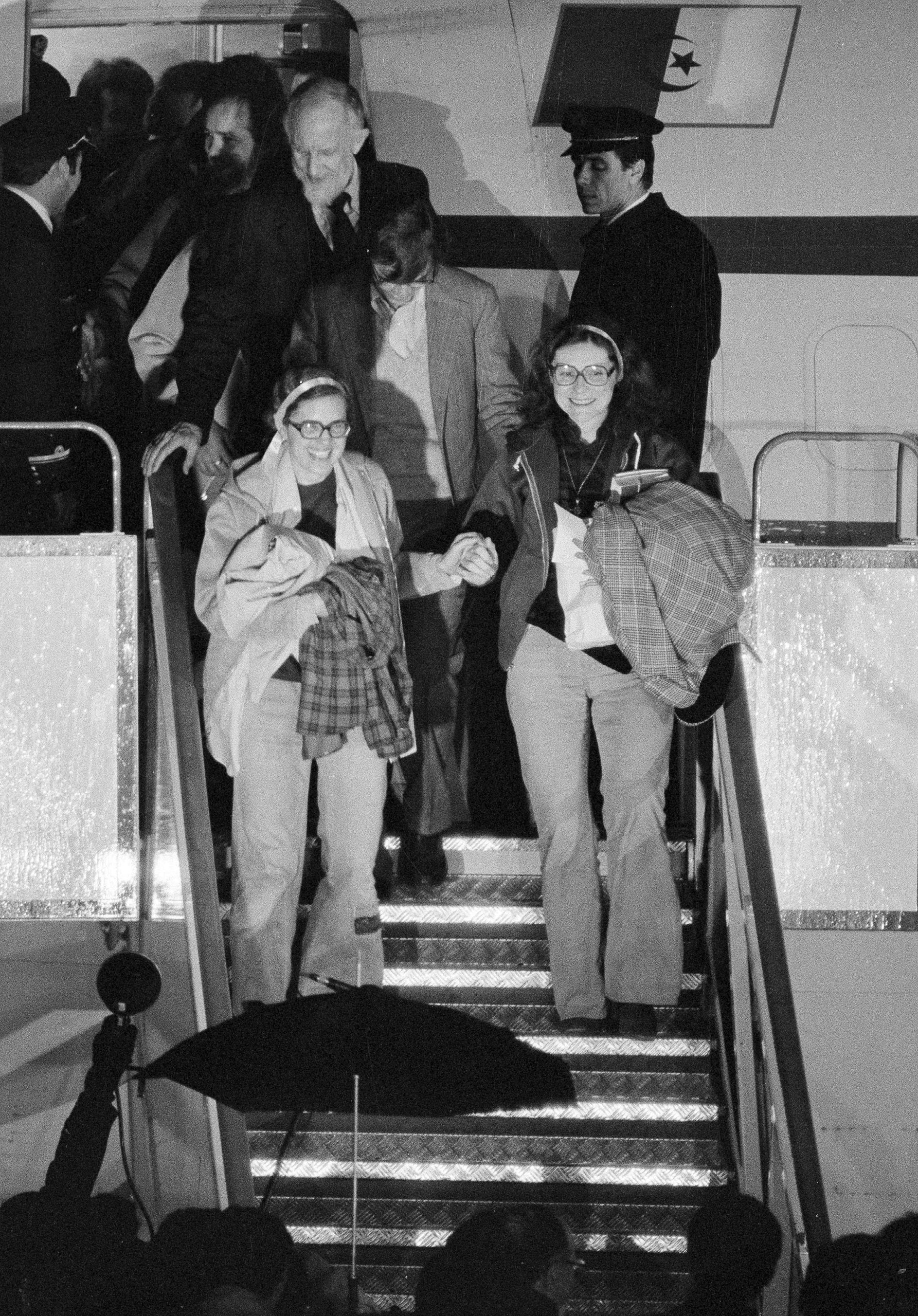 Kathryn Koob, right, and Elizabeth Ann Swift hold hands as they leave the Algerian aircraft which brought them to Algiers from Tehran at Algiers airport, Jan. 21, 1981. The women were two of the United States hostages held for 444 days in Iran.