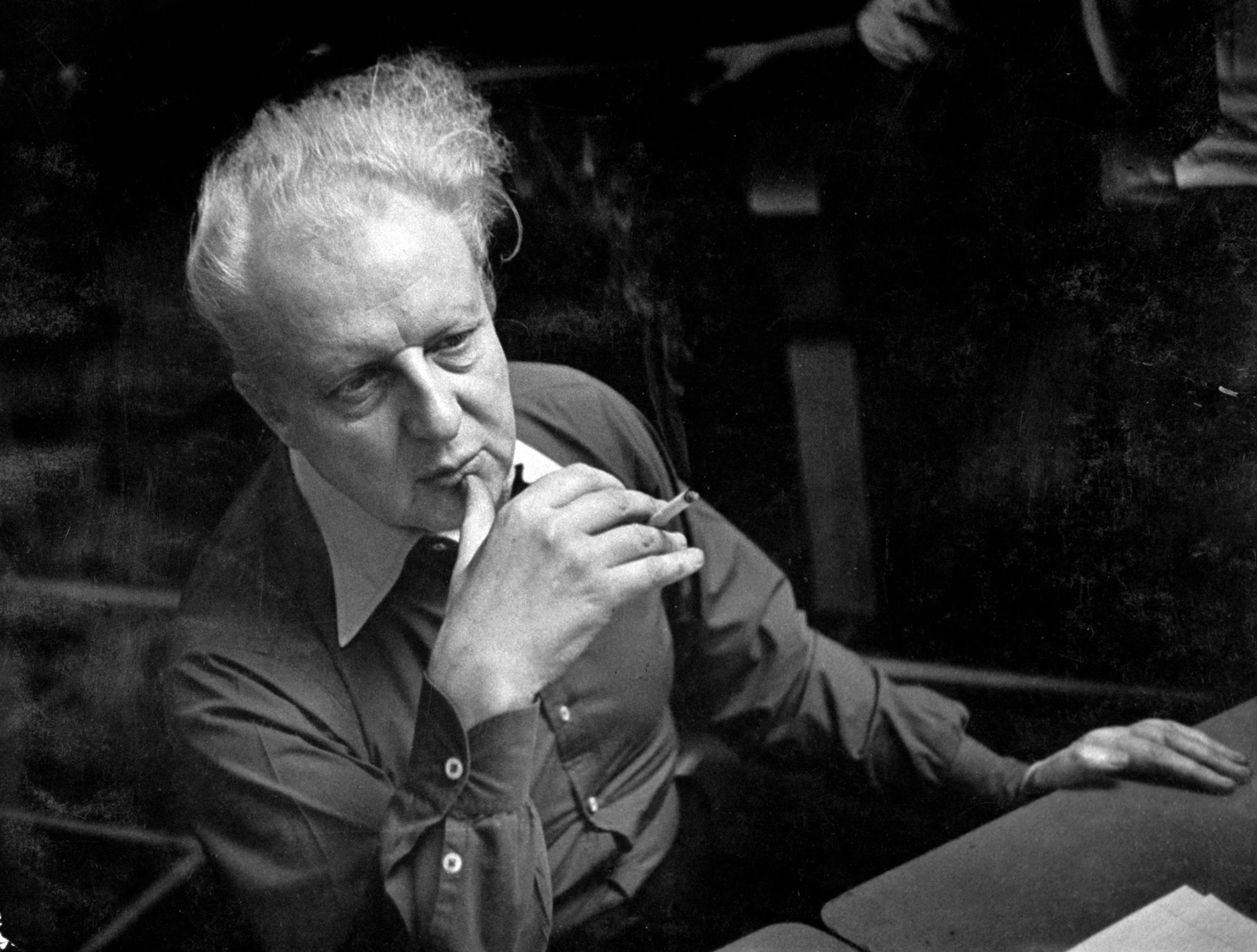 Leopold Stokowsky smokes a cigarette and listens during a recording session.