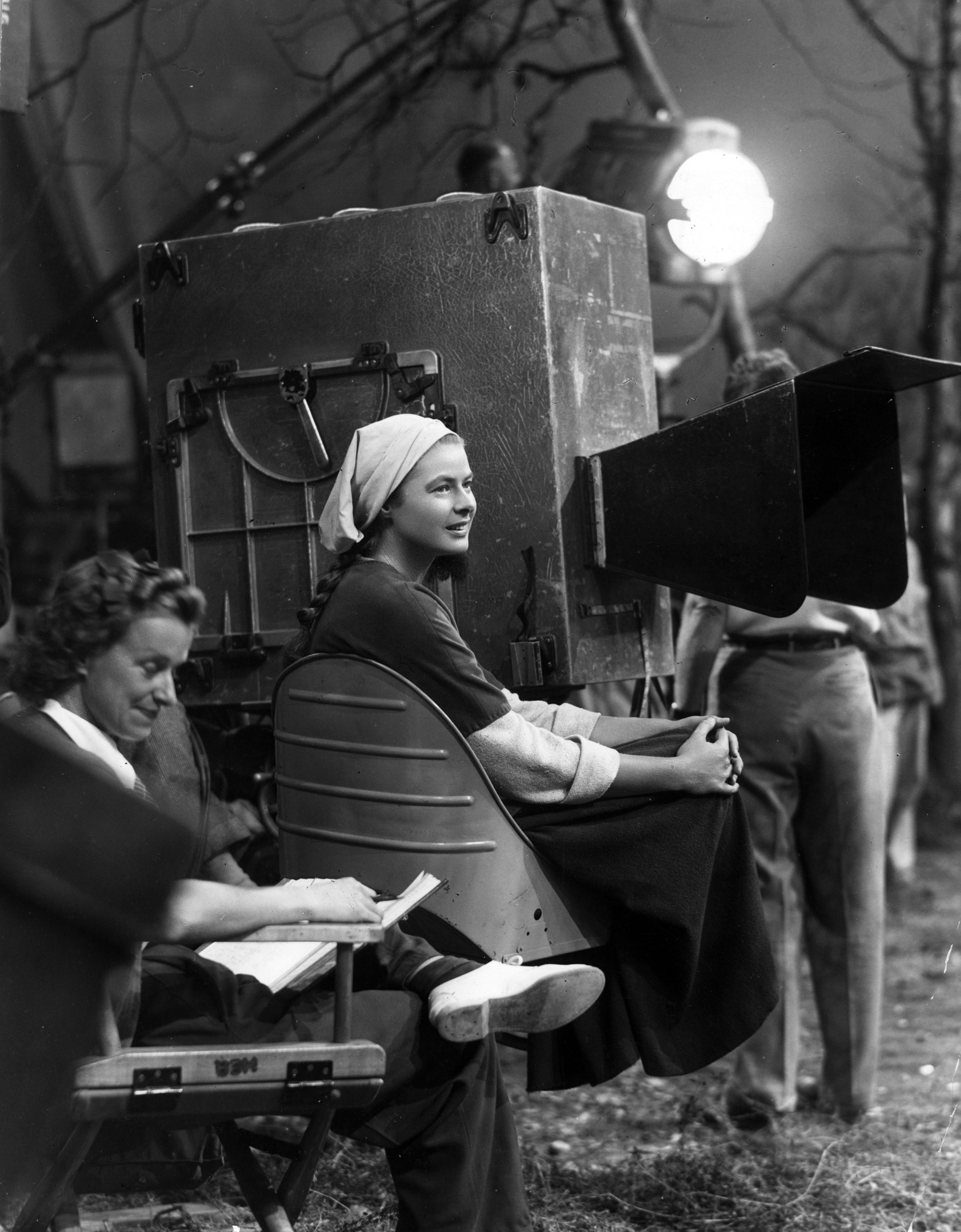 Ingrid Bergman sits next to the motion picture camera during a break in filming on the set of director Victor Fleming's film, 'Joan of Arc.' 1948.