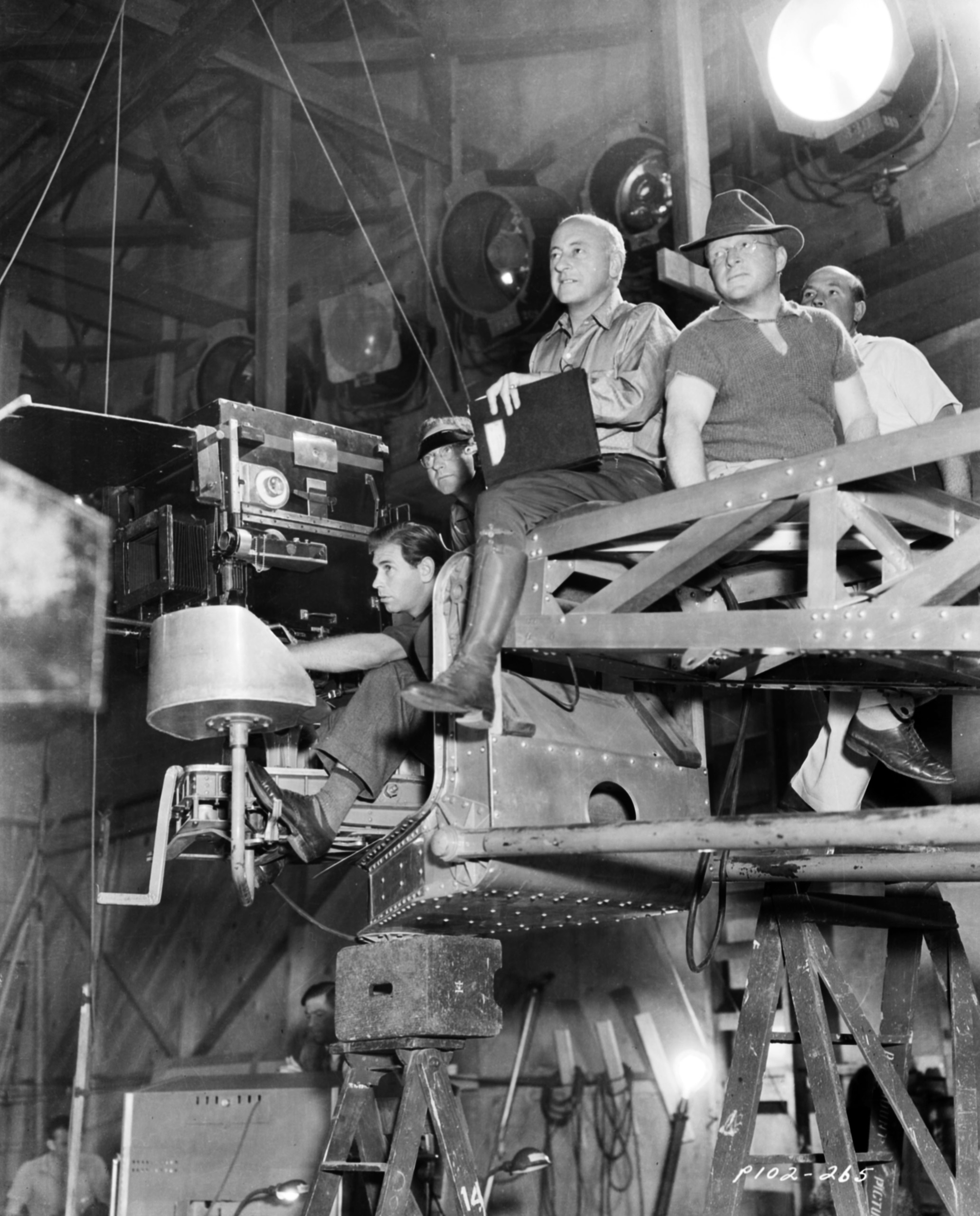 Cecil B DeMille sitting on a camera rig with members of his crew, on the set of the film 'Samson and Delilah', for Paramount Pictures, 1949.