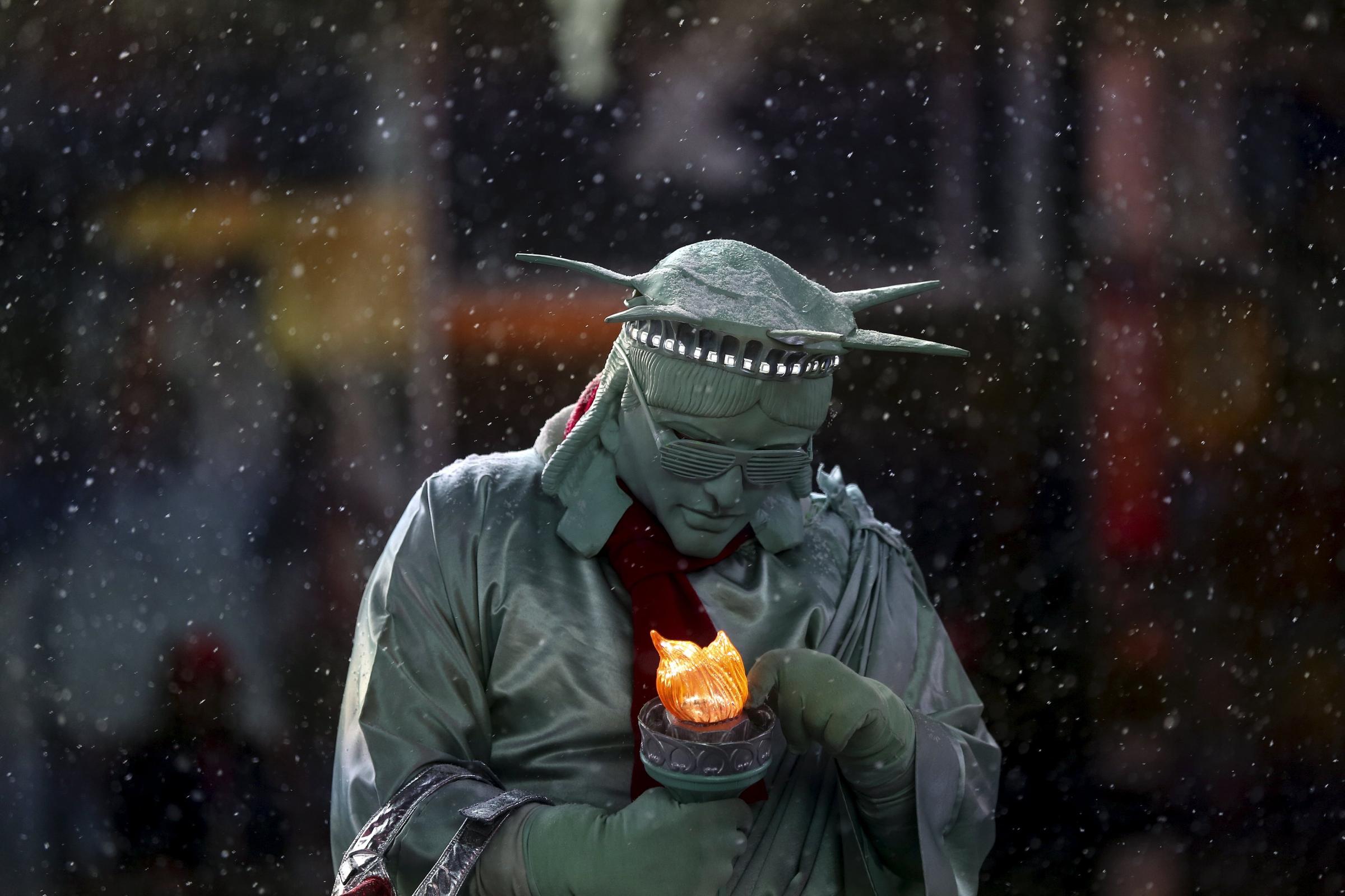A man dressed as the "Statue of Liberty" tries to fix his light as it begins to snow in Times Square in the Manhattan borough of New York
