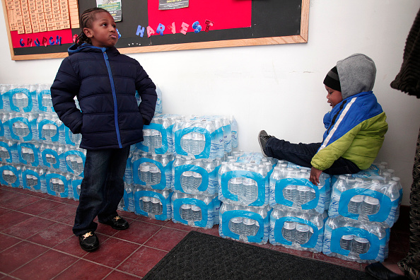 FLINT, MI - JANUARY 17:  Justin Roberson (L), age 6, of Flint, Michigan and Mychal Adams, age 1, of Flint wait on a stack of bottled water at a rally where the Rev. Jesse Jackson was speaking about about the water crises at the Heavenly Host Baptist Church January 17, 2016 in Flint, Michigan. U.S. President Barack Obama declared a federal emergency in Michigan, which will free up federal aid to help the city of Flint with lead contaminated drinking water. Michigan Gov. Rick Snyder requested emergency and disaster declarations after activating the National Guard to help the American Red Cross distribute water to residents.  Bill Pugliano&mdash;Getty Images (Bill Pugliano&mdash;Getty Images)