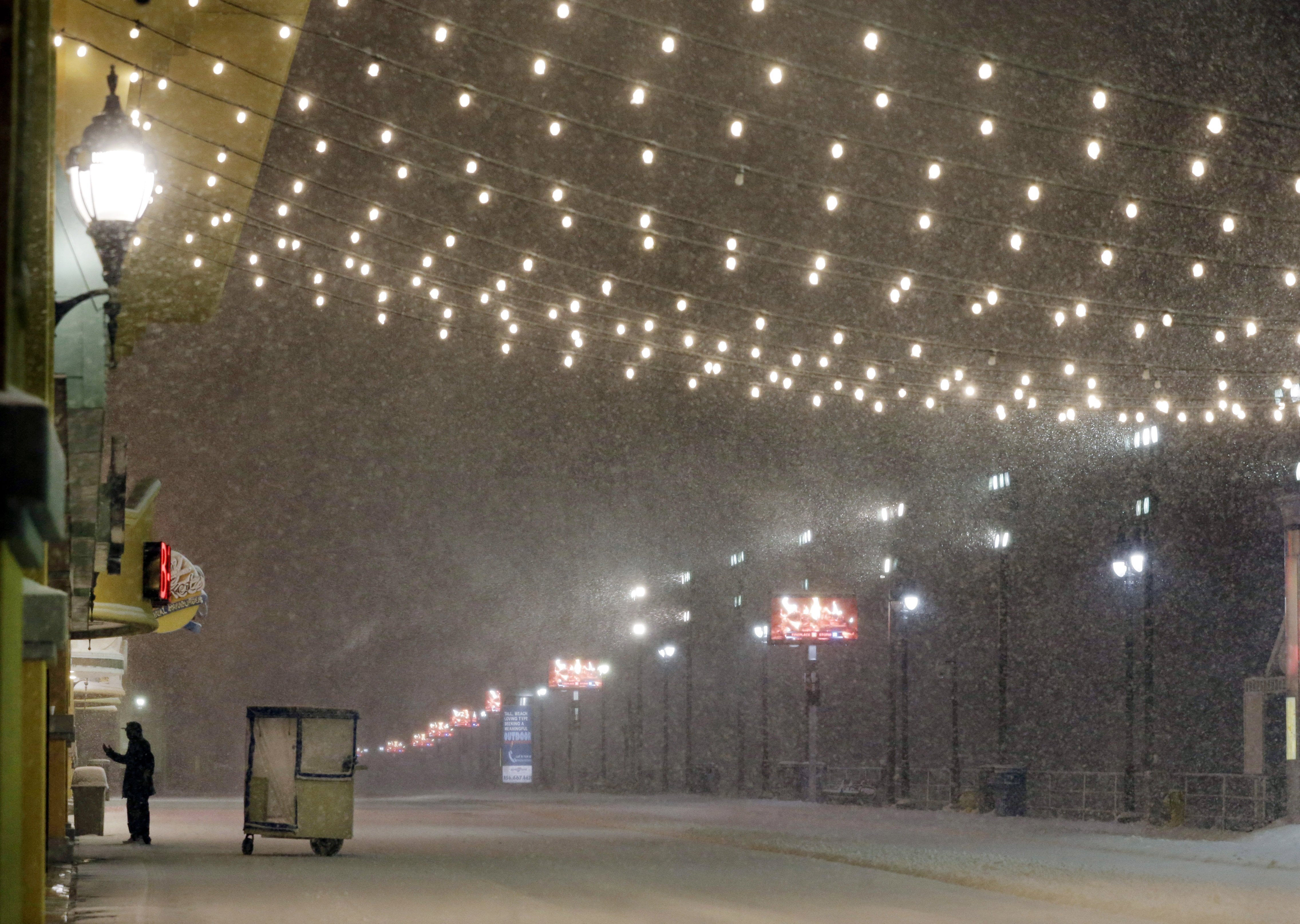 A stands near his Push cart during a snowstorm on Jan. 23, 2016, on the Atlantic City Boardwalk.