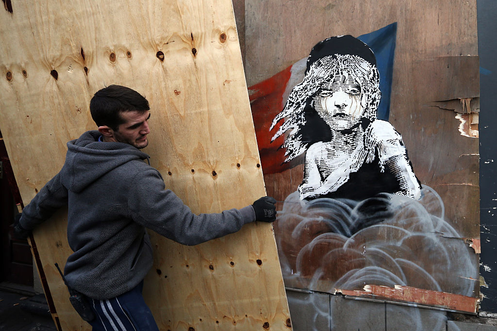 The artwork features a girl from the musical “Les Miserables” with tears in her eyes as a can of teargas billows up from the ground.
