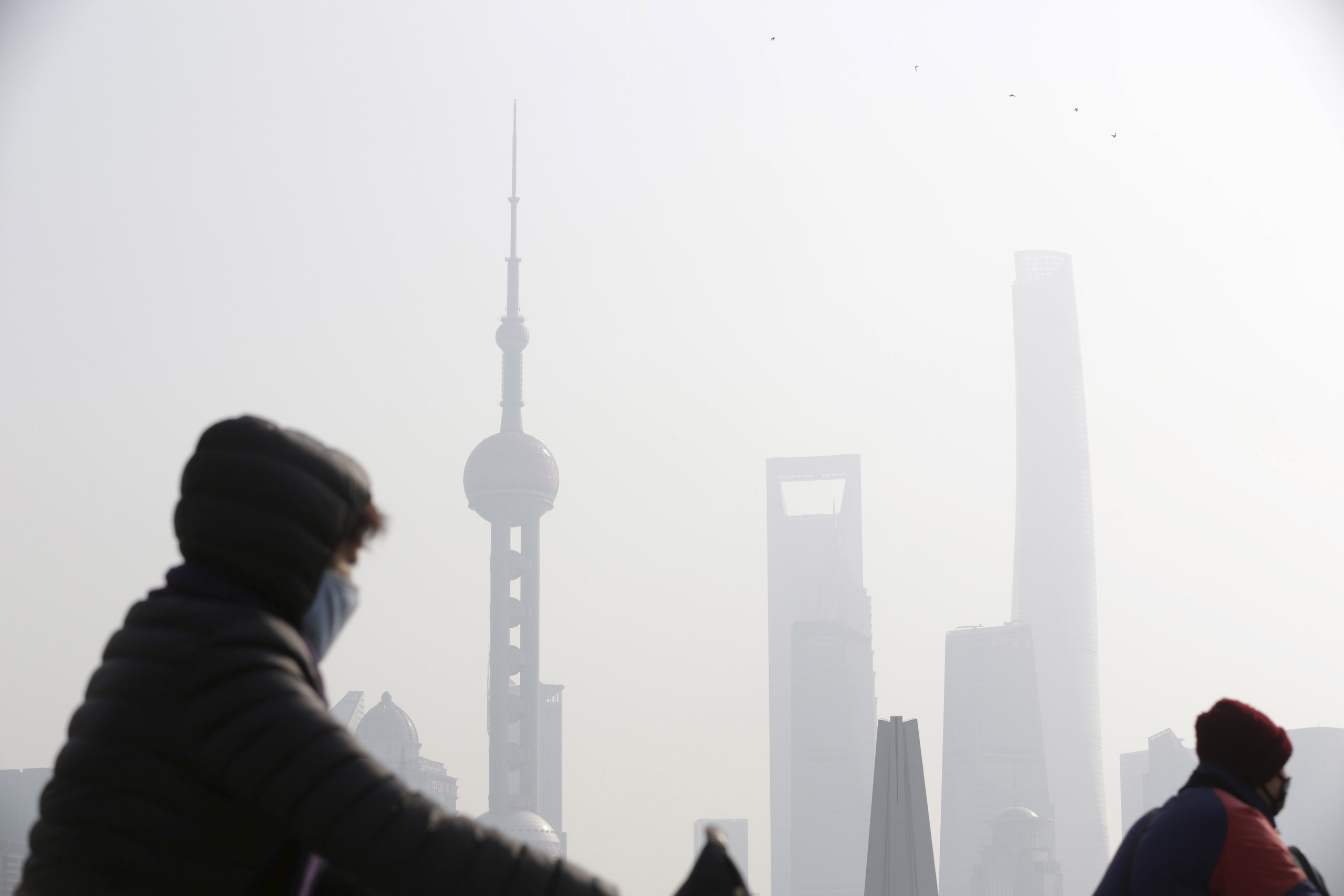 People wear protective masks near the Bund during a polluted day in Shanghai, China, January 19, 2016. Air pollution levels fell in most cities in China last year, environmental group Greenpeace said on Wednesday, but a humid and windless winter shrouded swaths of the country in choking smog, slowing improvement in the second half. Picture taken January 19, 2016. REUTERS/Aly Song      TPX IMAGES OF THE DAY      - RTX23563