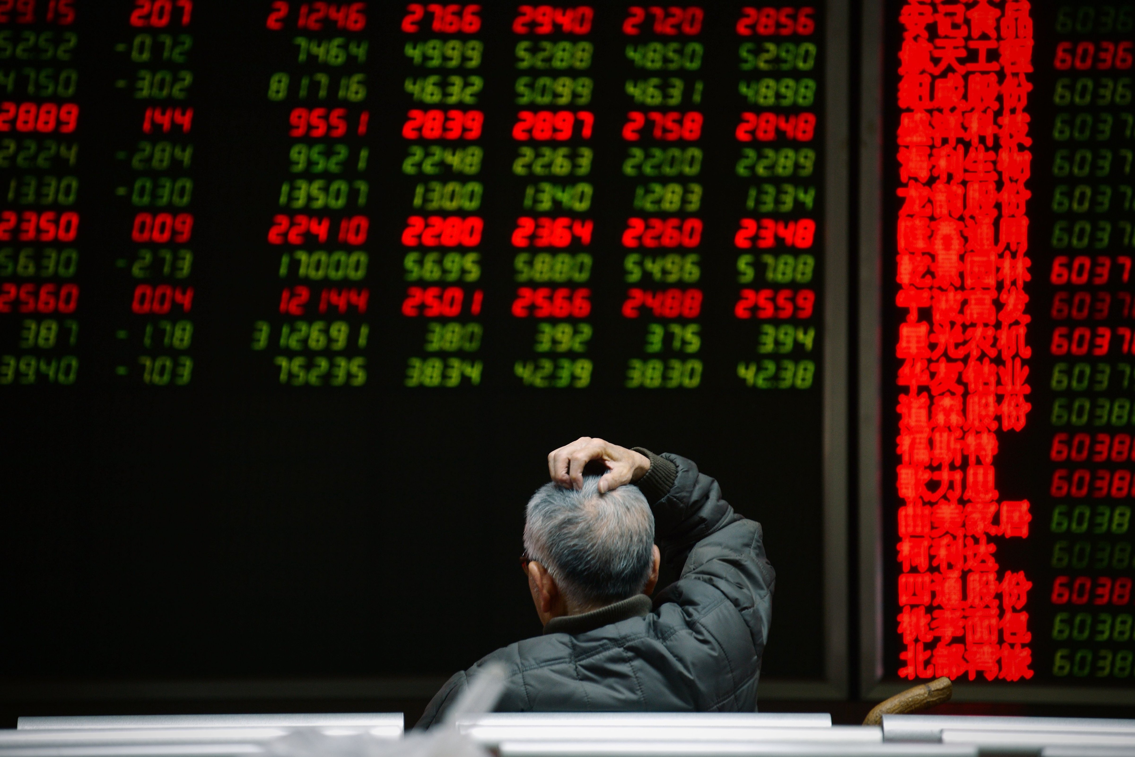 An investor looks at screens showing stock market movements at a securities company in Beijing on Jan. 14, 2016.