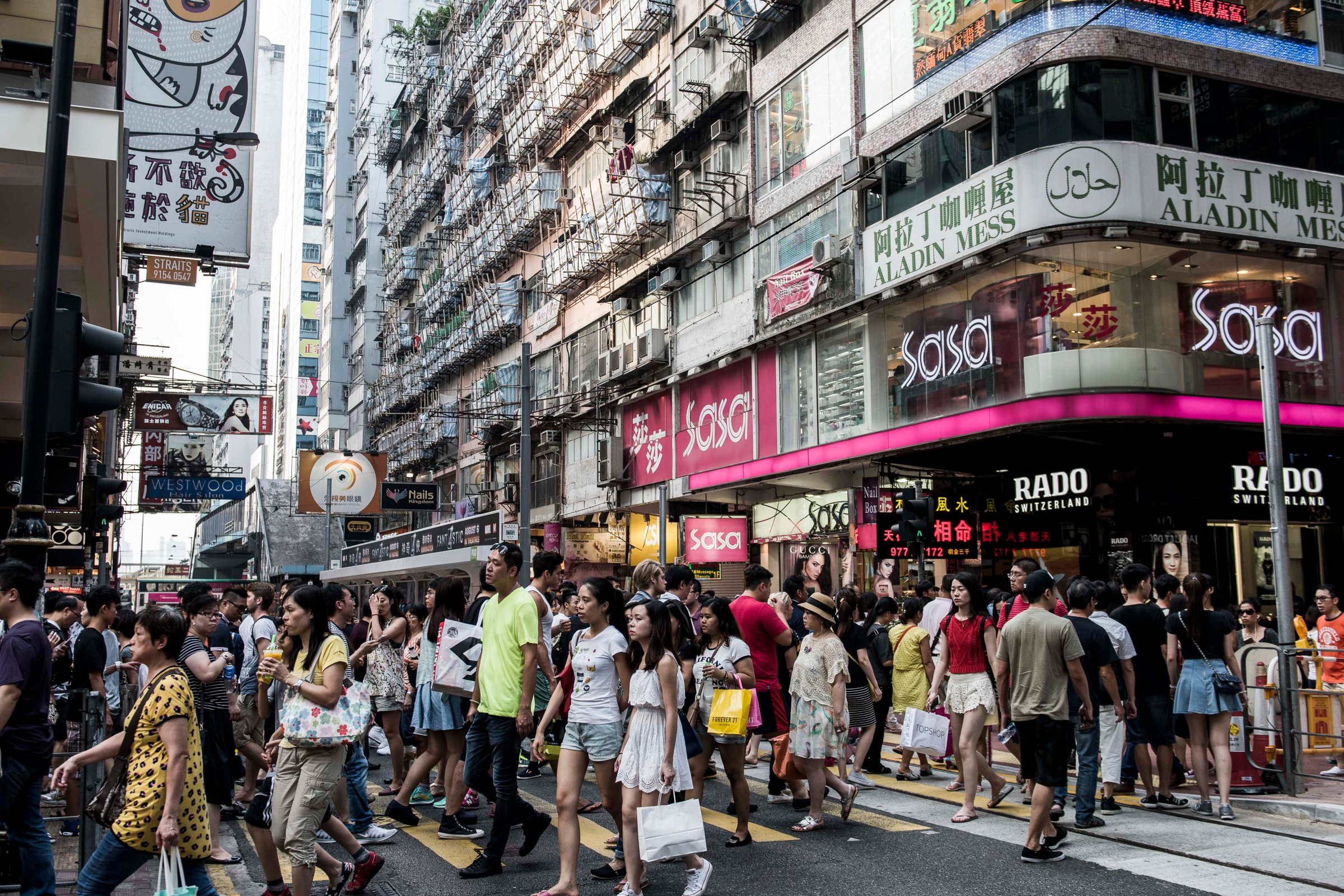 Shoppers and pedestrians cross a road on Russell Street in the Causeway Bay shopping district of Hong Kong, China, on Sunday, Aug. 9, 2015. Landlords on Hong Kong's Russell Street a year ago could boast the highest retail rents in the world. Now they are adjusting to a new reality. Photographer: Xaume Olleros/Bloomberg