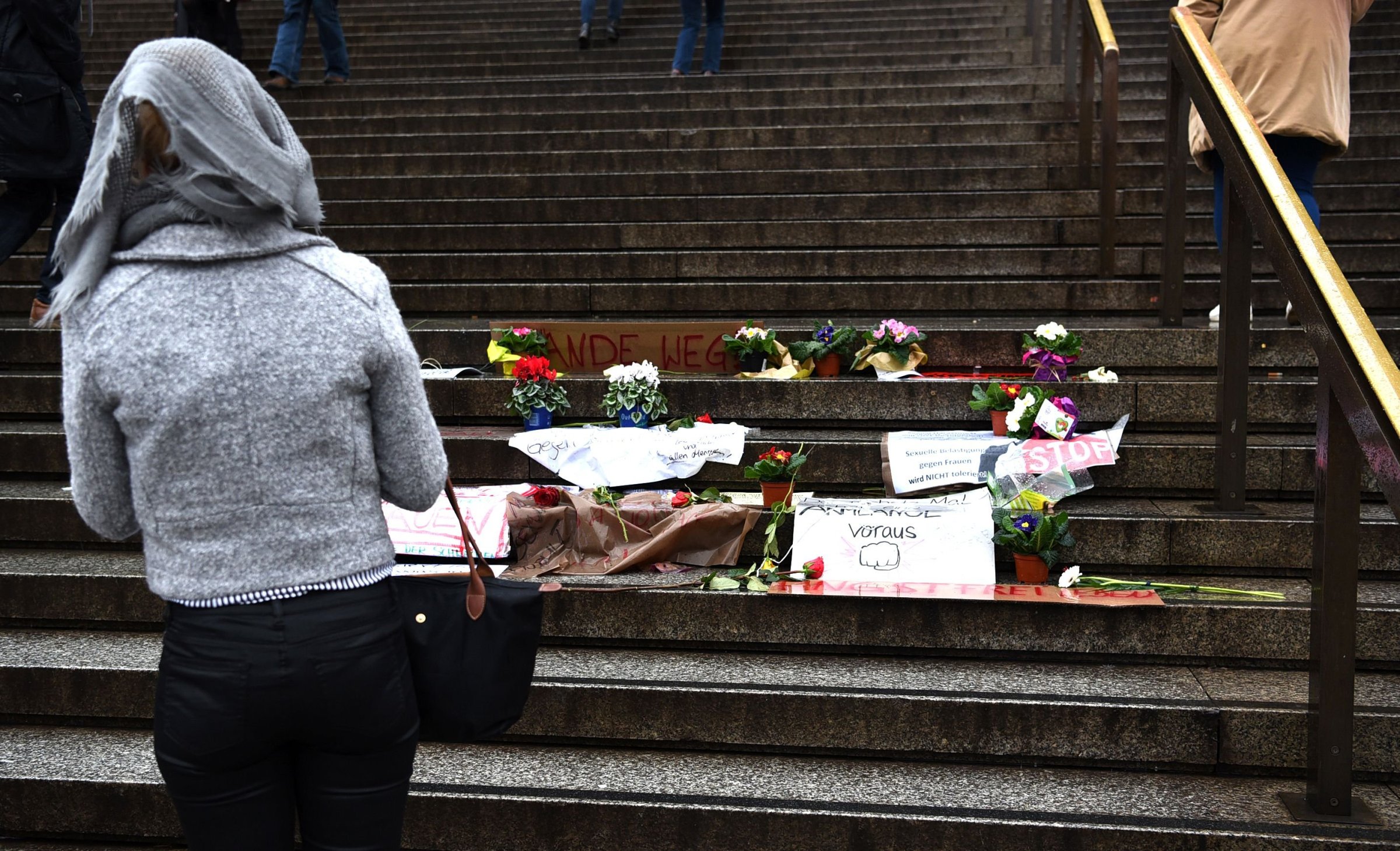 A woman looks at flowers and letters of protest that are laid down on the steps in front of the Cologne main train station in Cologne, western Germany on Jan. 11, 2016.