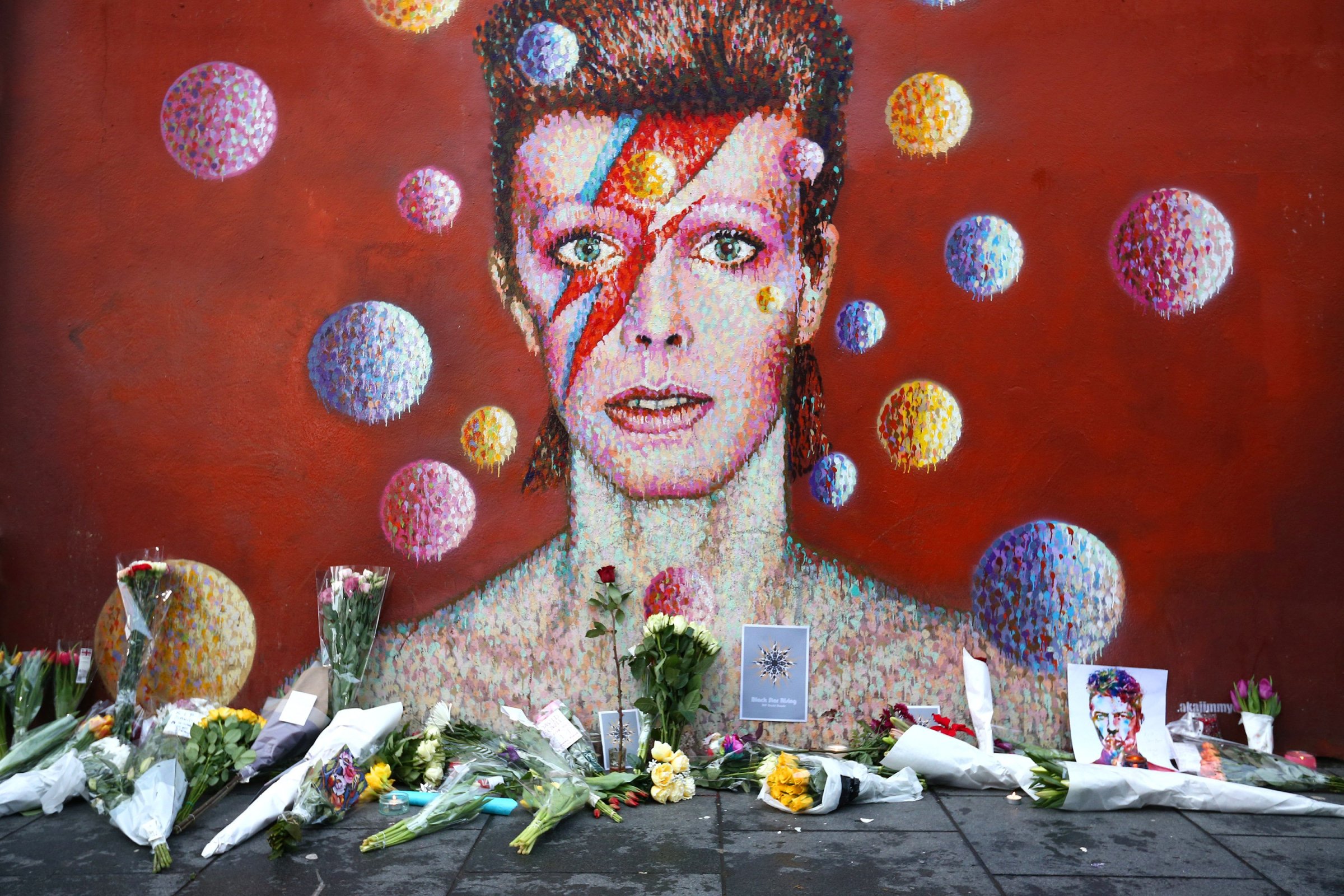 Flowers are laid beneath a mural of David Bowie in Brixton, England on Jan. 11, 2016. British music and fashion icon David Bowie died earlier today at the age of 69 after a battle with cancer.