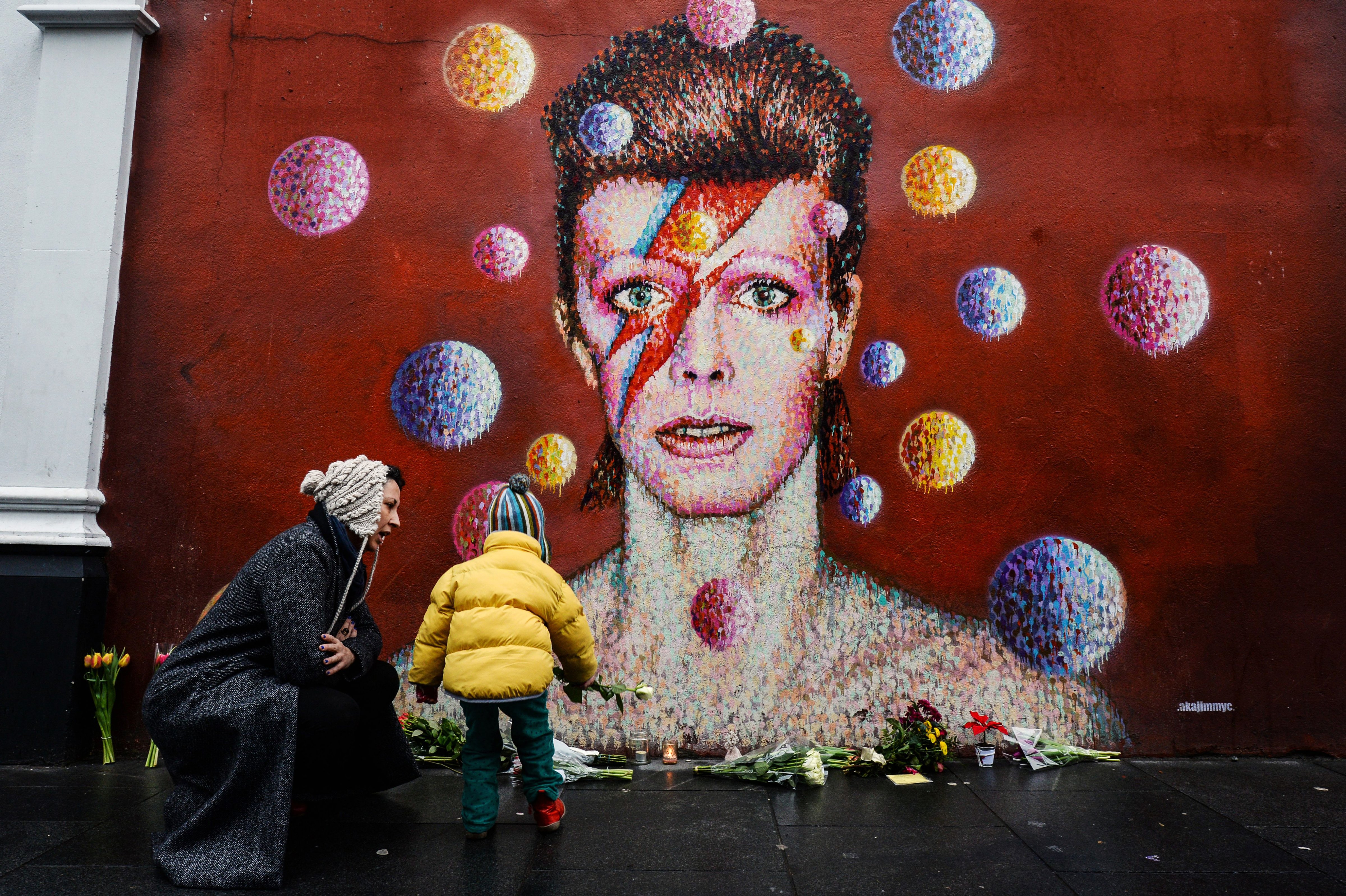 Flowers are left beneath a mural of British singer David Bowie, painted by street artist James Cochran, known as Jimmy C, following the announcement of Bowie's death, in Brixton, south London, on Jan. 11, 2016. (Chris Ratcliffe—AFP/Getty Images)