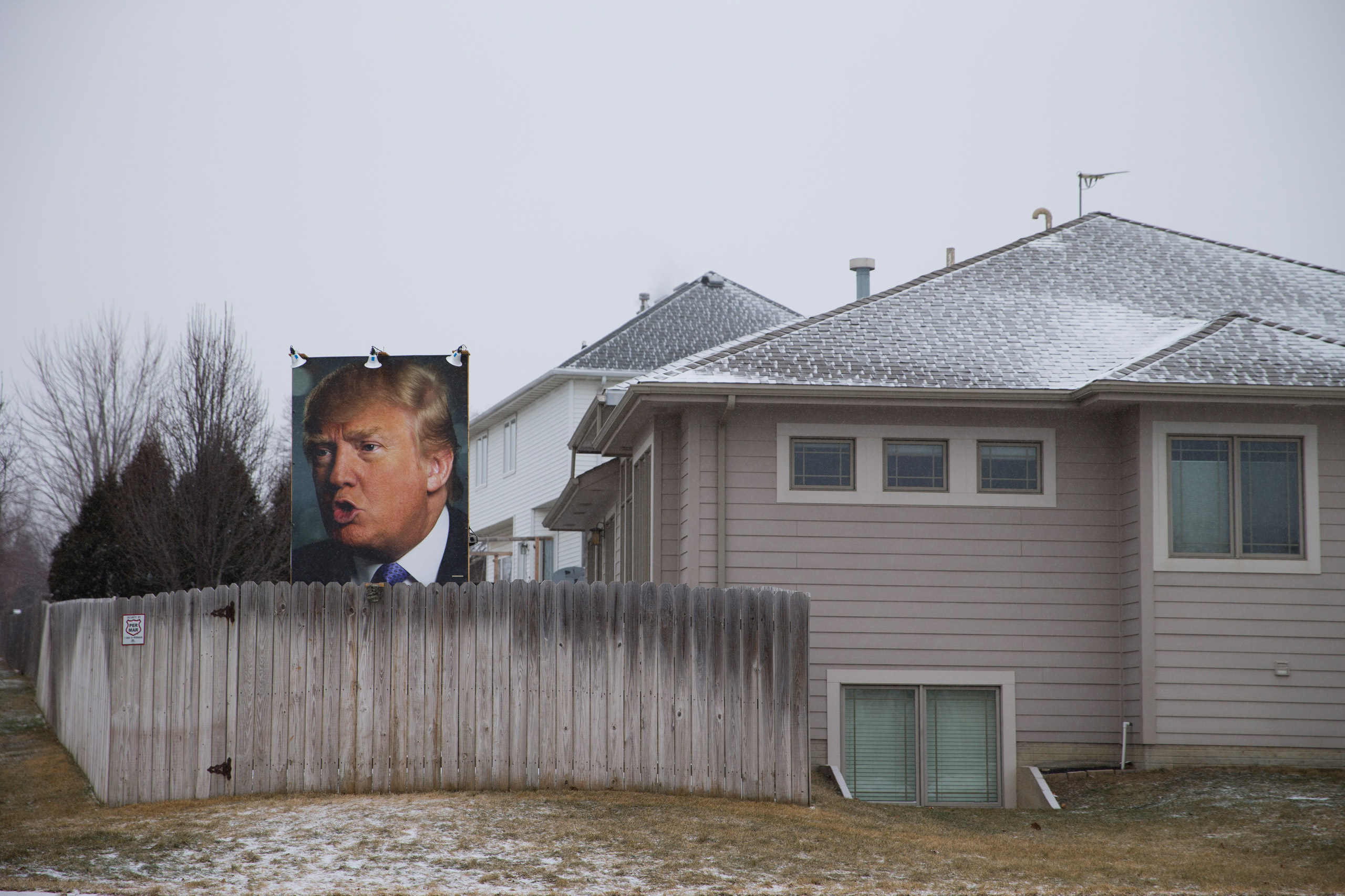 A photo of Republican presidential candidate Donald Trump hangs outside a home Tuesday, Jan. 19, 2016, in West Des Moines, Iowa. (AP Photo/Jae C. Hong)