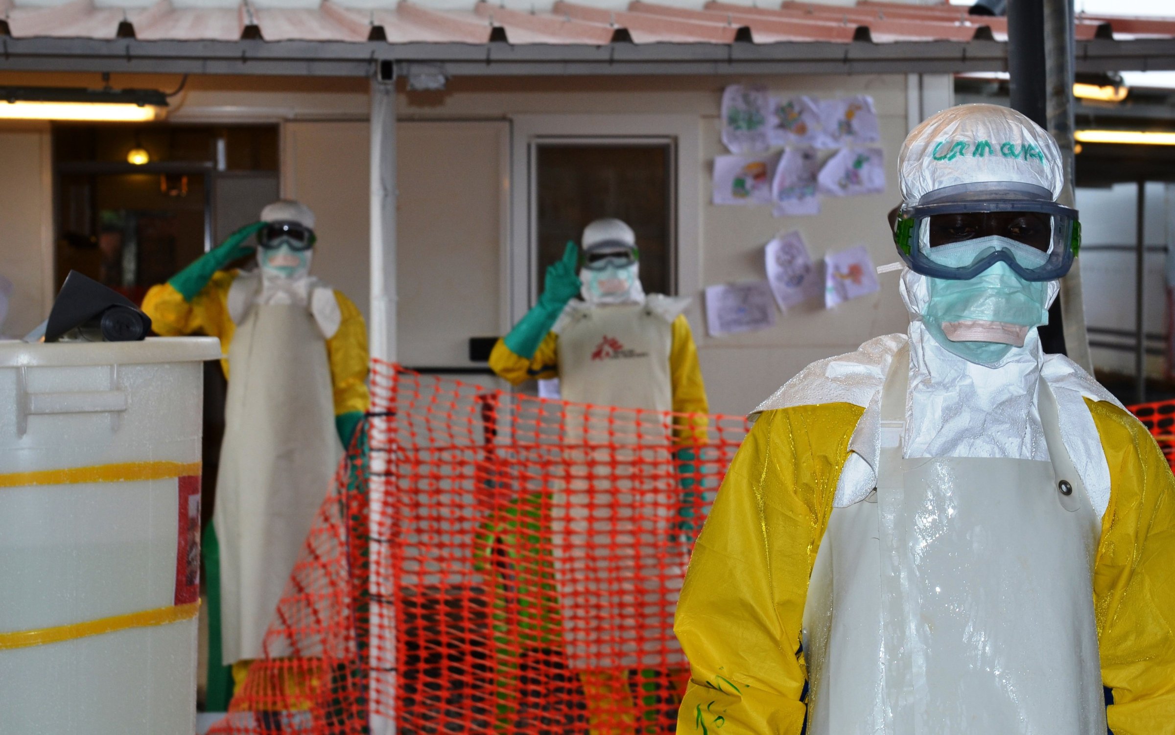 Health workers wearing protective gear gesture at the Nongo ebola treatment centre in Conakry, Guinea, on August 21, 2015.