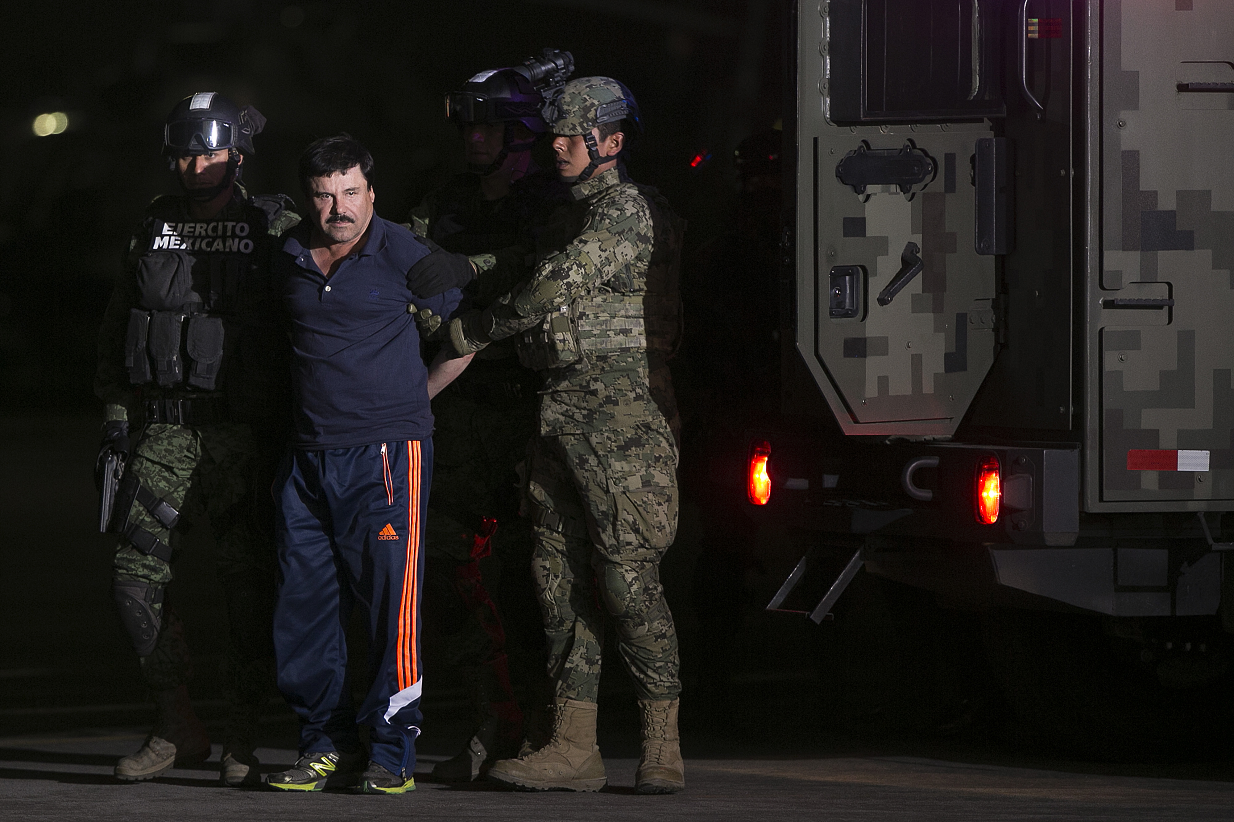 Joaquin Guzman, the world's most wanted-drug trafficker, second left, is escorted by Mexican security forces at a Navy hangar in Mexico City, Mexico, on Jan. 8, 2016.