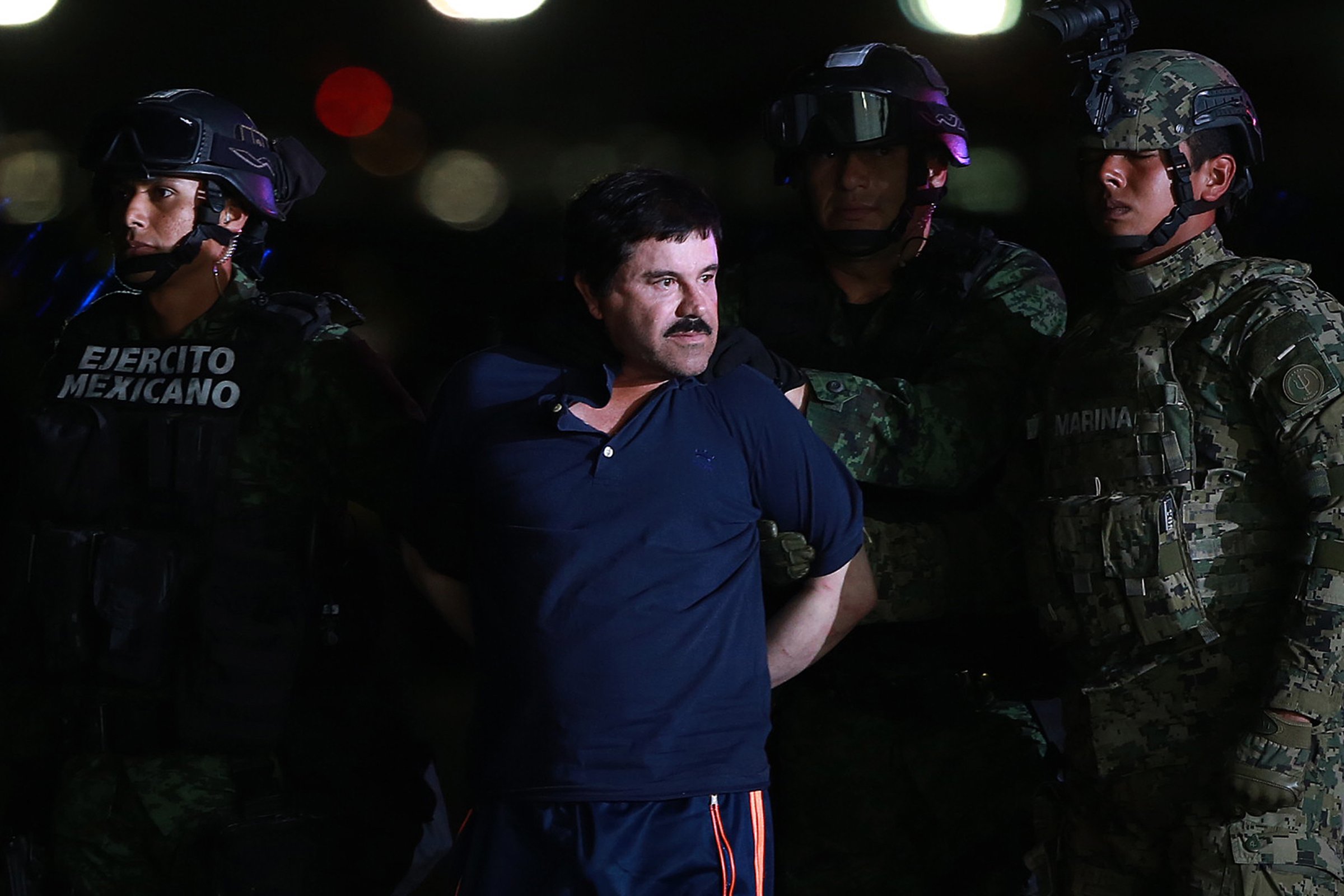 Joaquin Guzman, the world's most wanted-drug trafficker, center, is escorted by Mexican security forces at a Navy hangar in Mexico City, Mexico, on Jan. 8, 2016.