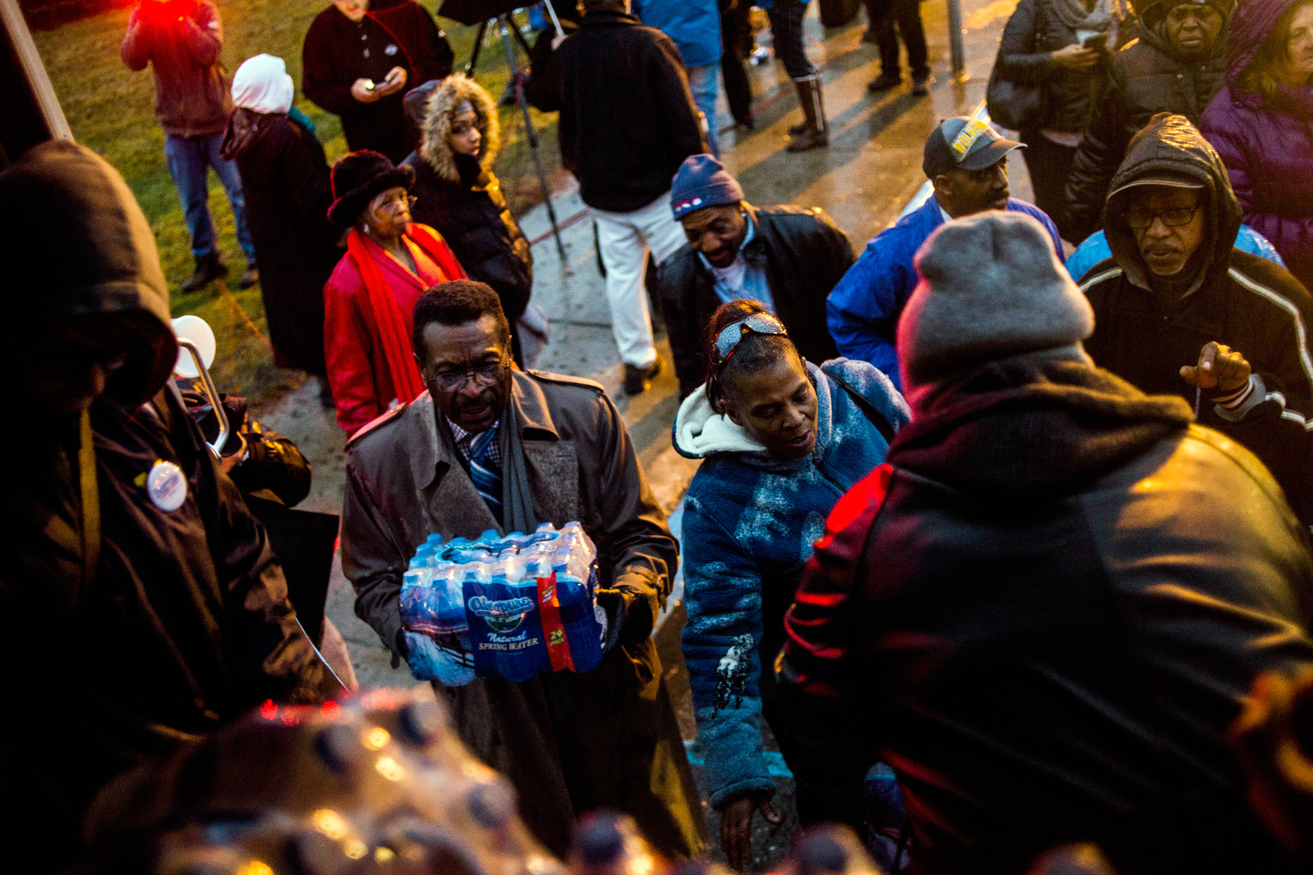 Flint residents line up for free bottled water as activists protest outside of City Hall to protest Michigan Gov. Rick Snyder's handling of the water crisis Friday, Jan. 8, 2016 in Flint. Mich. (Jake May/The Flint Journal-MLive.com via AP) LOCAL TELEVISION OUT; LOCAL INTERNET OUT; MANDATORY CREDIT
