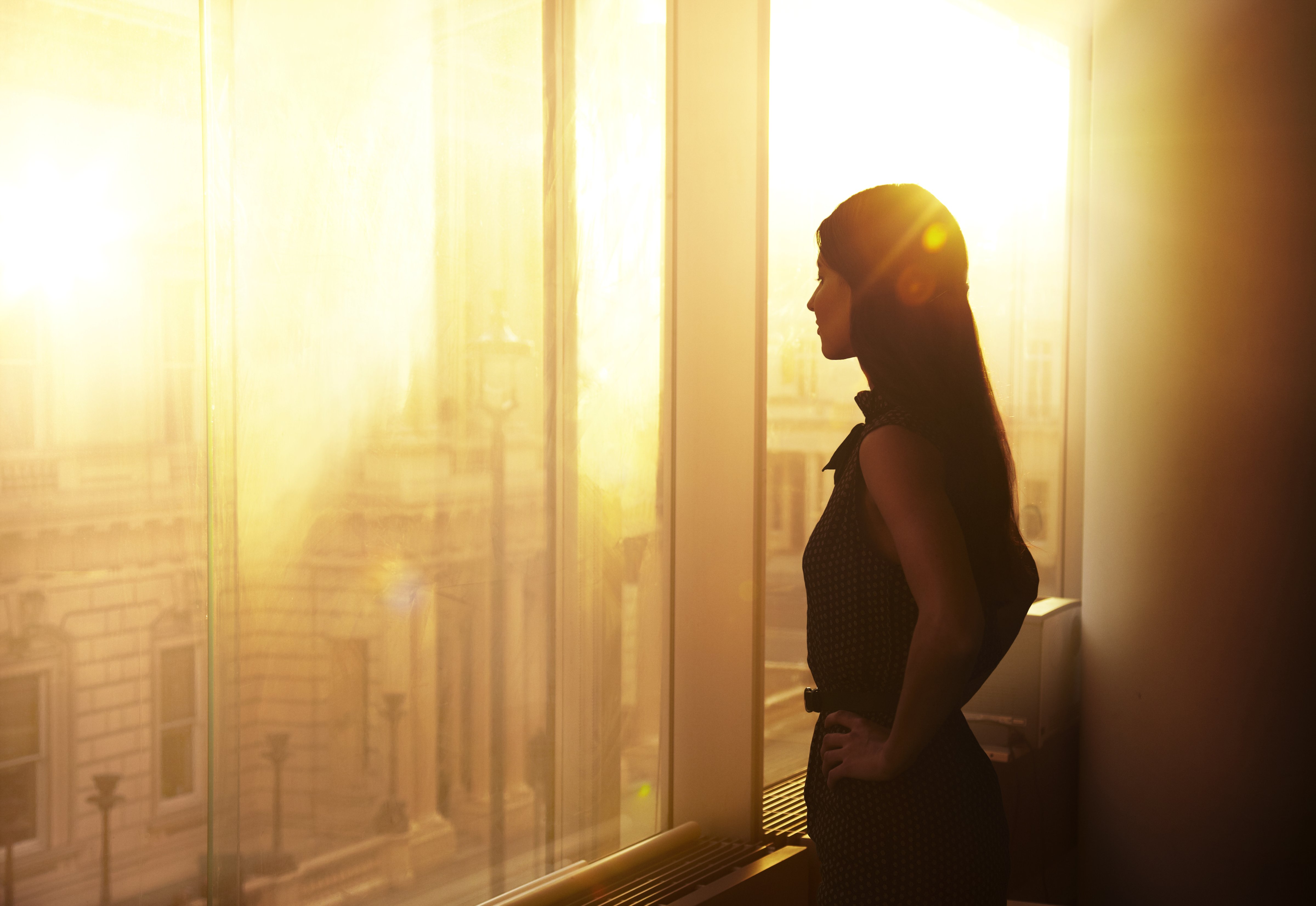 Businesswoman looking over the city at sunrise (Oli Kellett—Getty Images)