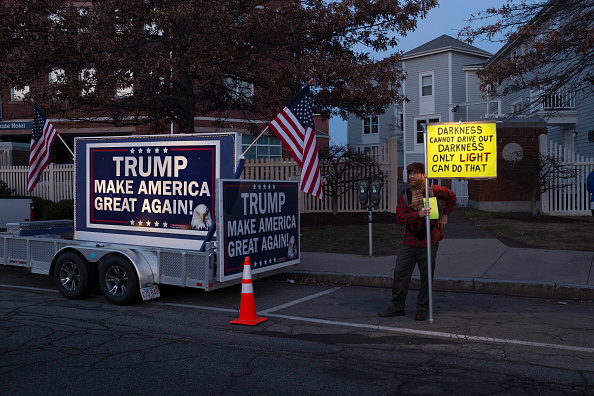 A protester stands beside a pro-Trump billboard outside the Sheraton Portsmouth Harborside Hotel where Republican Presidential candidate Donald Trump is due to speak at the New England Police Benevolent Association Meeting December 10, 2015 in Portsmouth, New Hampshire.