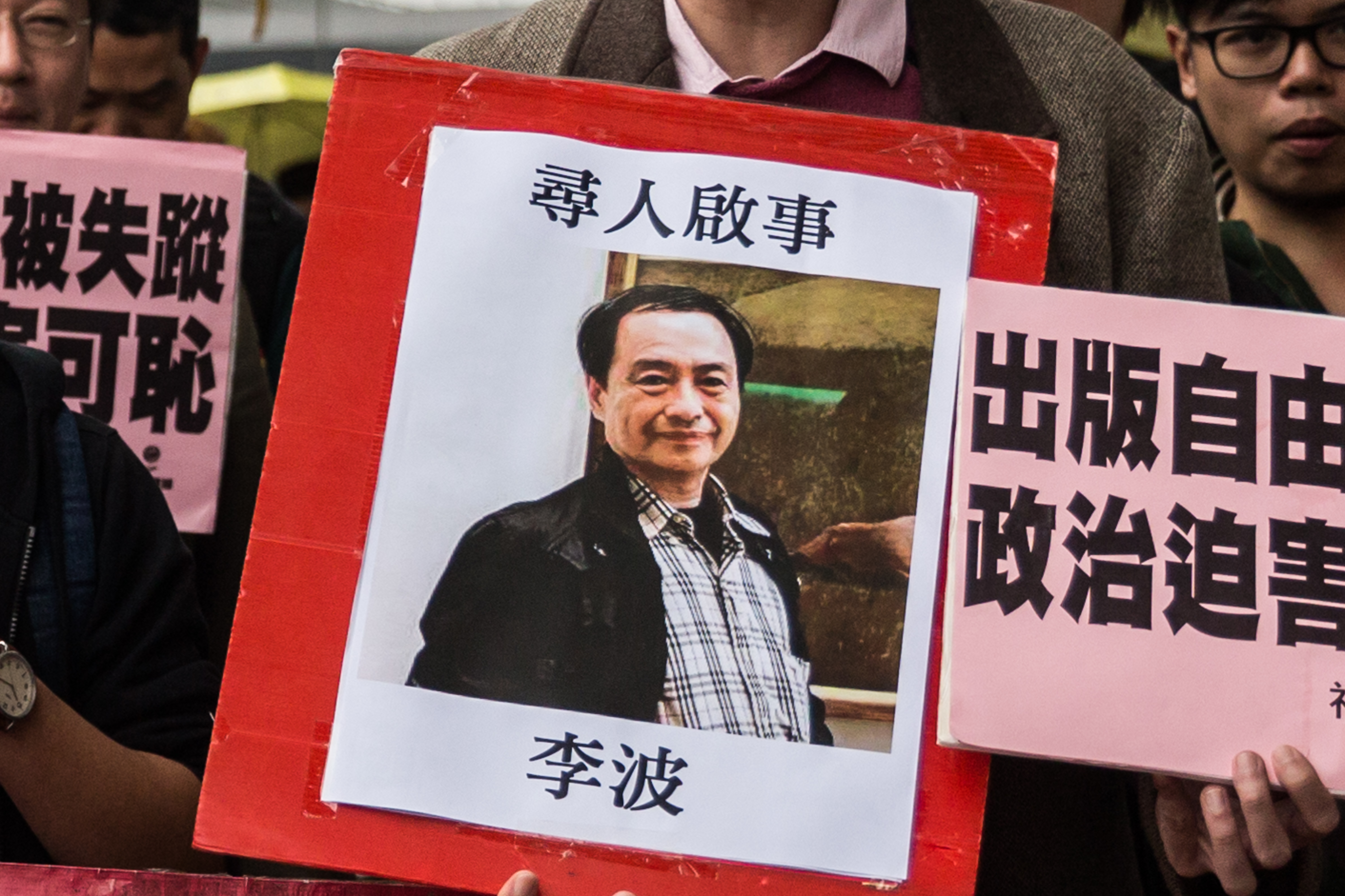 In this picture taken on January 3, 2016, a protestor holds up a missing person notice for Lee Bo, 65, the latest of five Hong Kong booksellers from the same Mighty Current publishing house to go missing, as they walk towards China's Liaison Office in Hong Kong. (ANTHONY WALLACE—AFP/Getty Images)