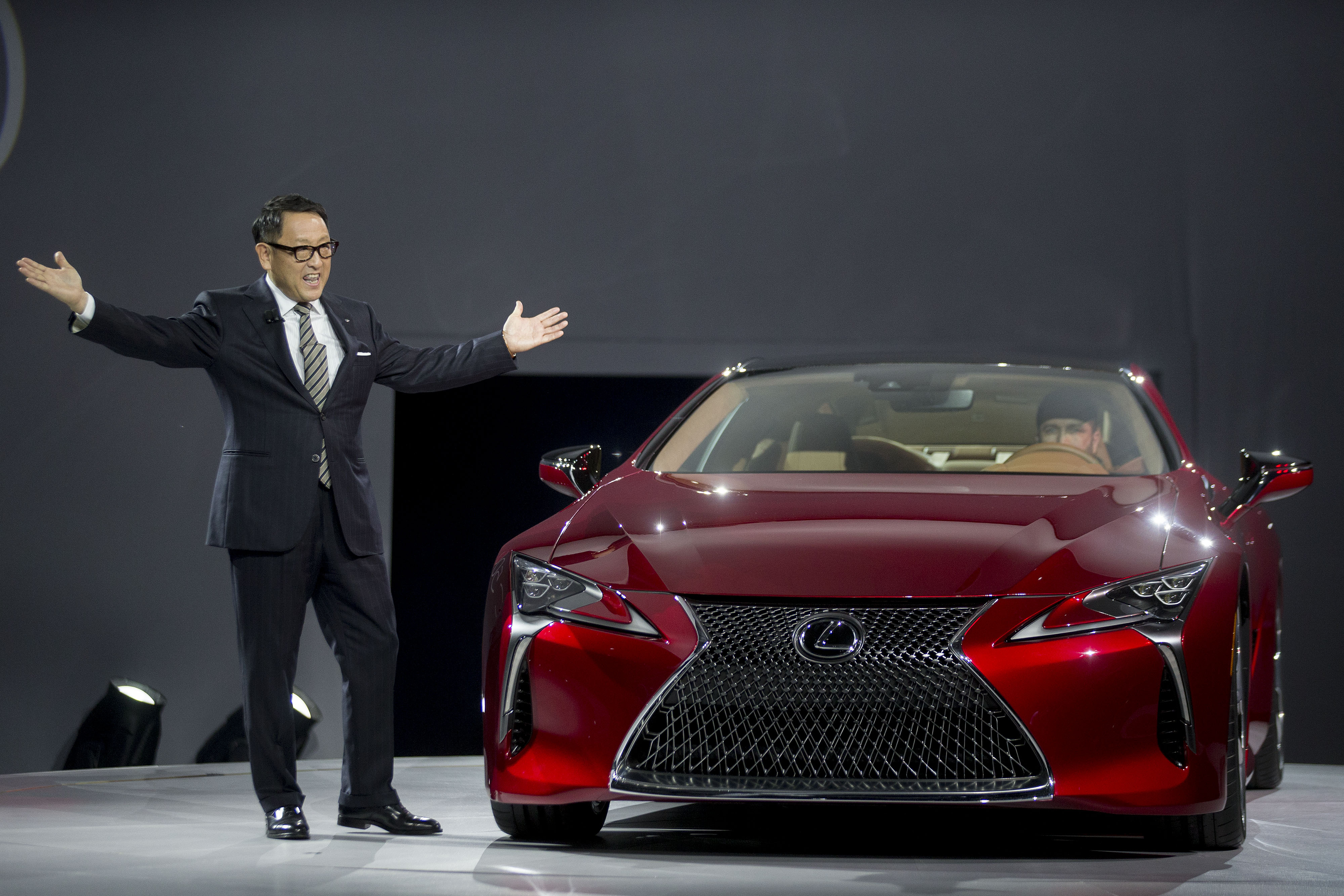 Akio Toyoda, president of Toyota Motor Corp., gestures while standing next to a Lexus LC 500 after being unveiled during the 2016 North American International Auto Show (NAIAS) in Detroit, Michigan, U.S., on Monday, Jan. 11, 2016. (Bloomberg&mdash;Bloomberg via Getty Images)