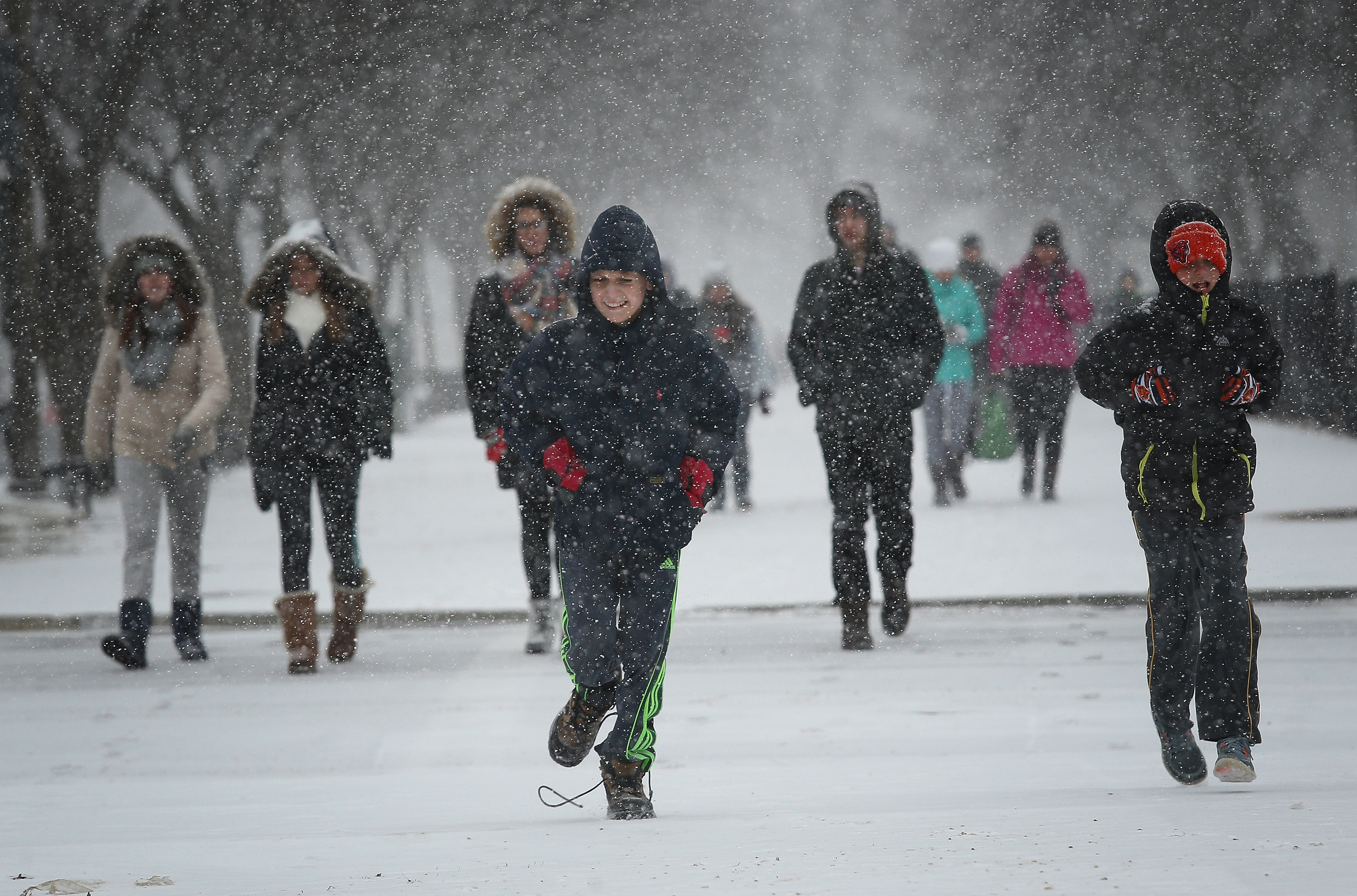 School children run along the National Mall as snow begins to fall in Washington, DC on Jan. 22, 2016.