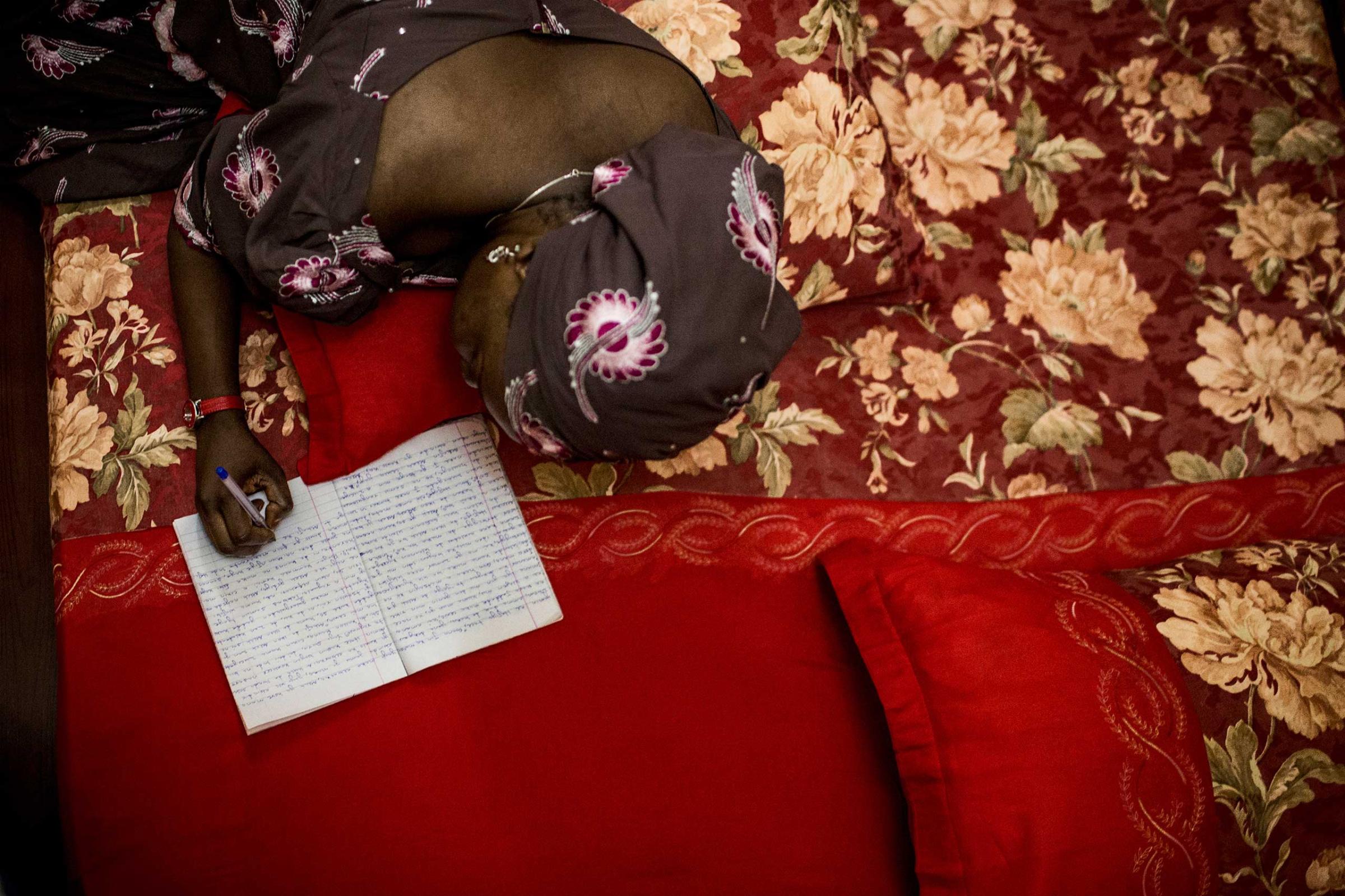 Khadija Gudaji works on her novel while laying in bed at her home in Kano, Northern Nigeria, Sept. 29, 2013.