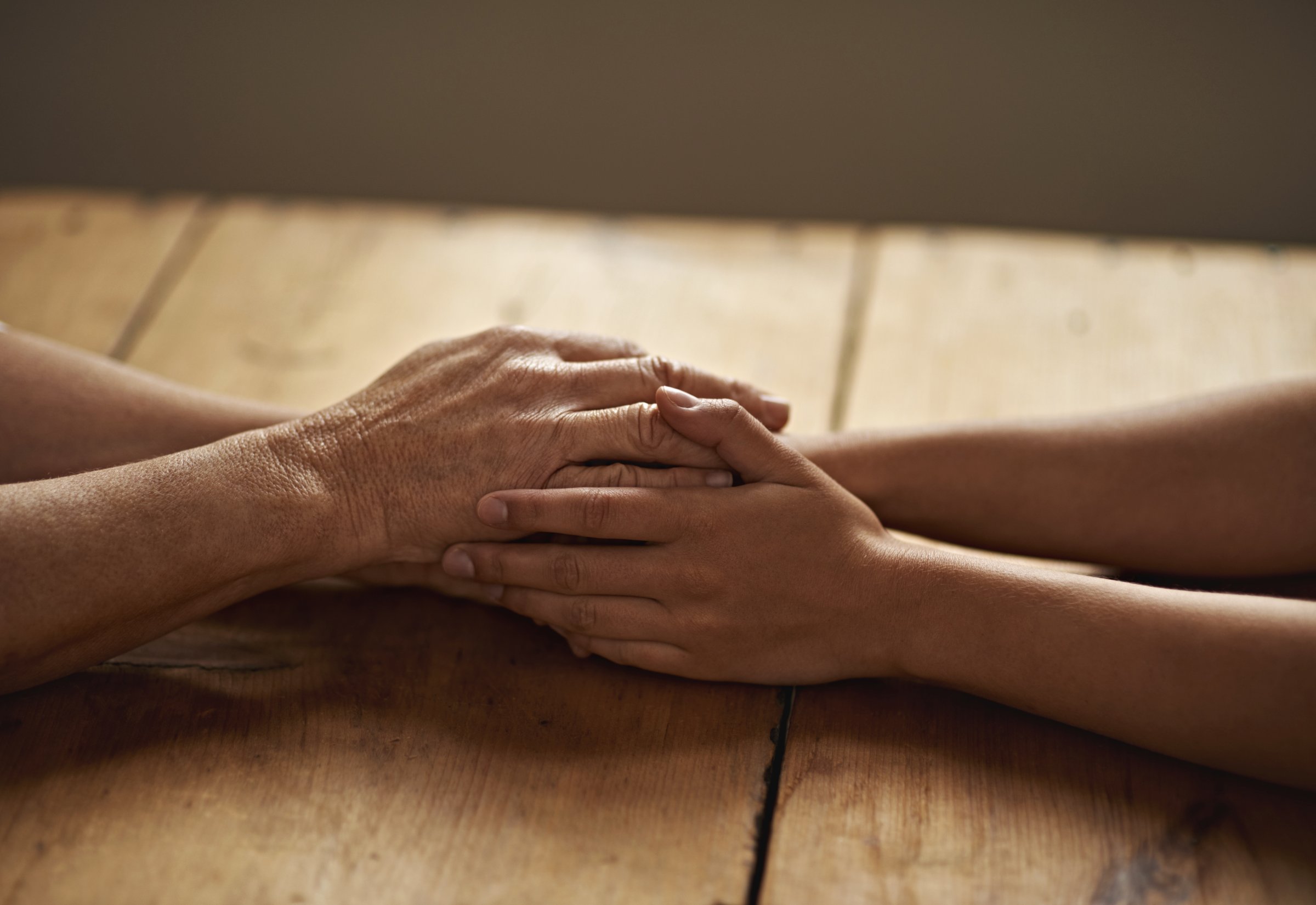 holding-hands-comforting-wooden-table