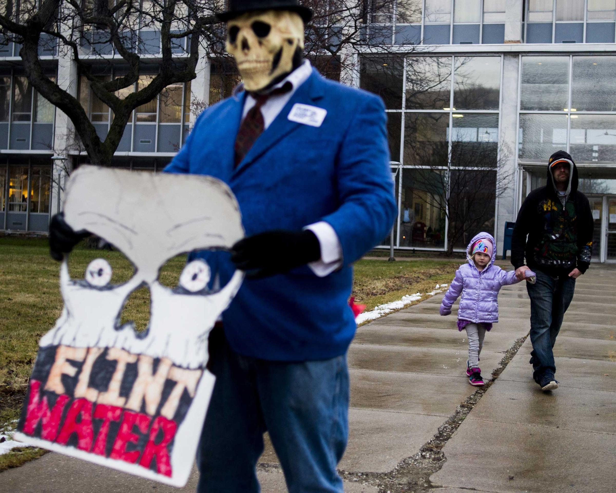 Flint resident Mike Hickey holds the hand of his daughter Natielee, 4, as they walk past activists outside of City Hall to protest Michigan Gov. Rick Snyder's handling of the water crisis Jan. 8, 2016 in Flint. Mich.