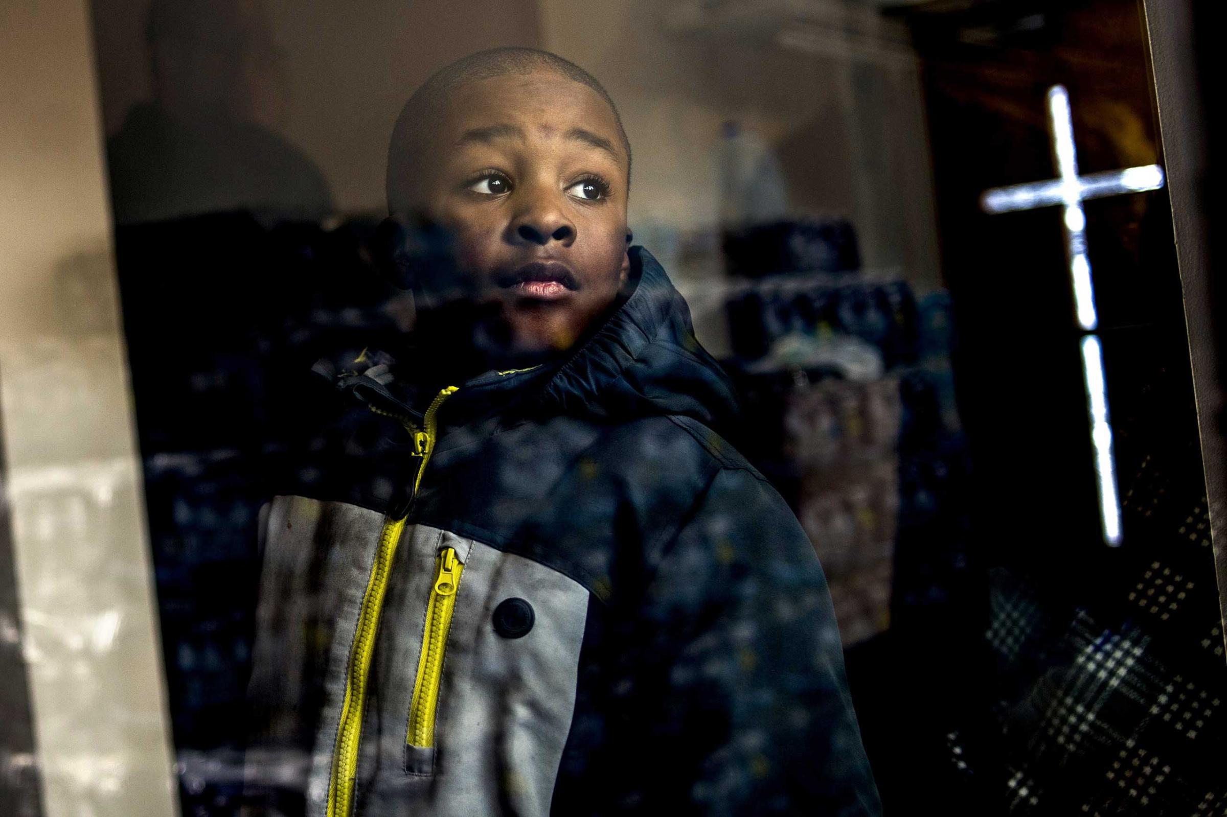 Detroit resident Jaiden Ellis, 8, looks at stacks of free bottled water to be given to the congregation while the Rev. Jesse Jackson, a civil rights leader, discusses the ongoing Flint water crisis on Jan. 17, 2016, in Flint, Mich. The water became contaminated after Flint switched from the Detroit water system to the Flint River as a cost-cutting move.