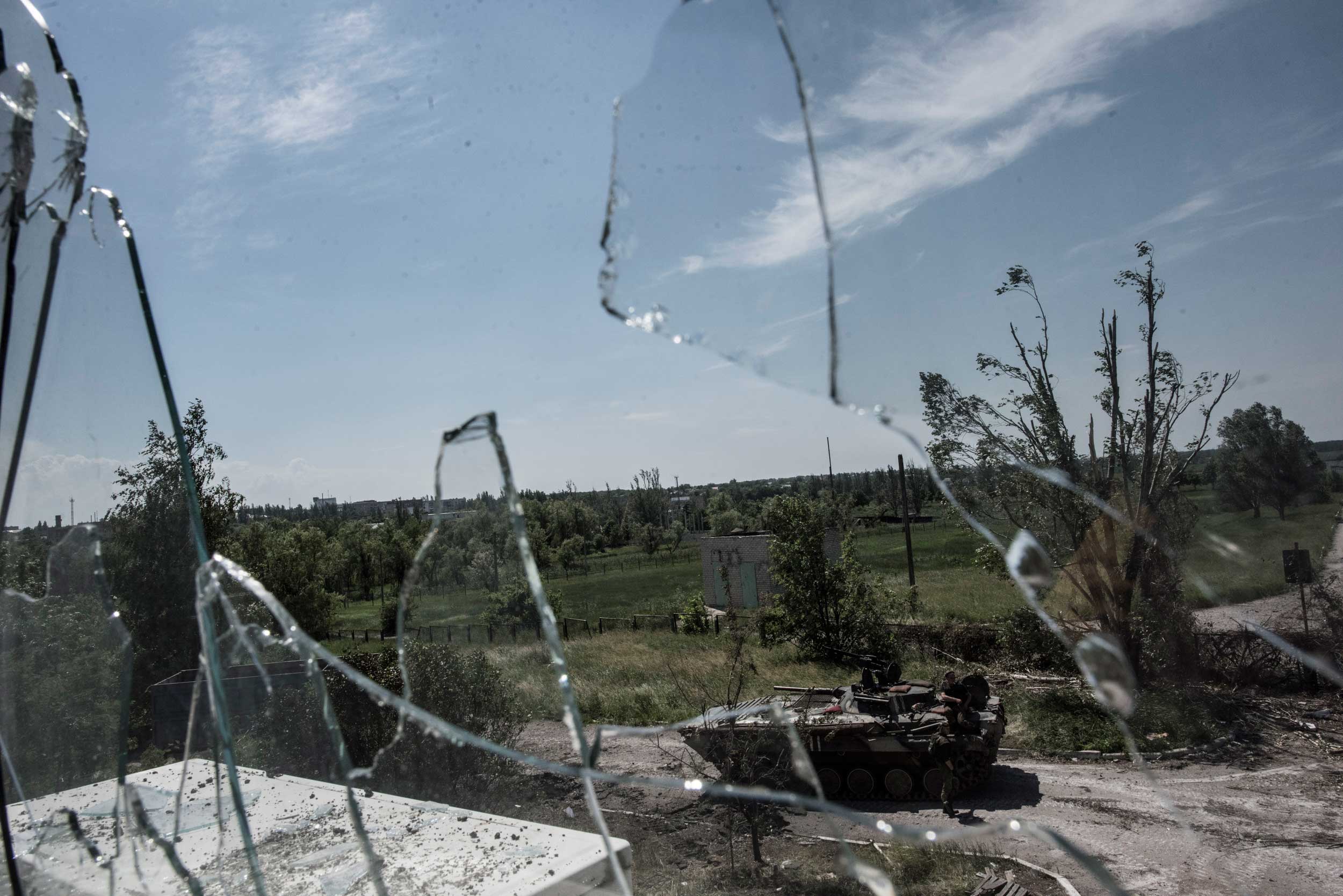 Ukrainian soldiers with an armoured personnel carrier (APC) are photographed through broken glass near the division line with separatists in Marinka, near Donetsk, eastern Ukraine,  June 5, 2015.