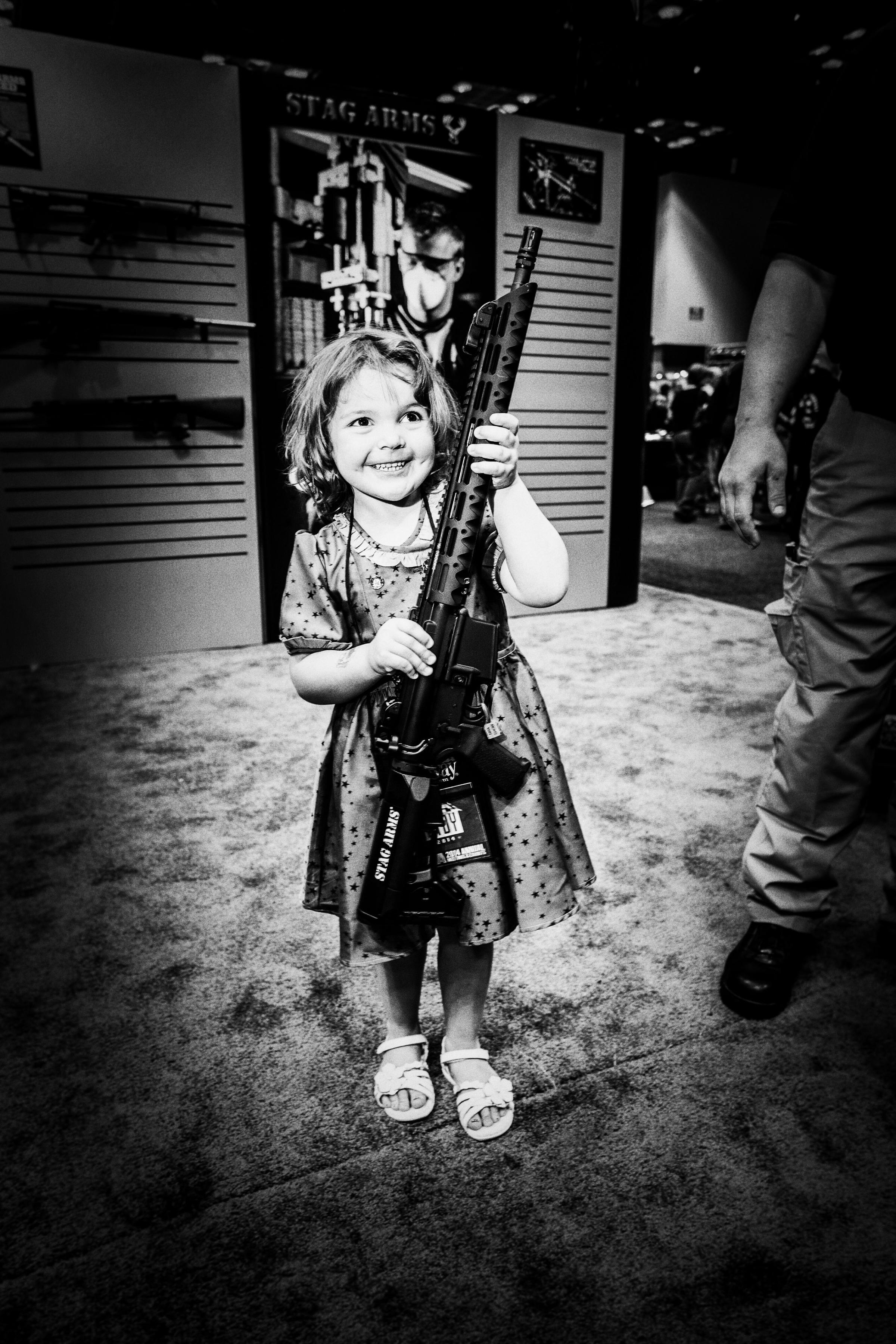 The National Rifle Association annual convention in Indianapolis Indiana.  the exhibit hall was over nine acres of guns and products for guns and over 60,000 people attended the convention.  4 year old violet ogle with a assault rifle on the in the exhibitors hall that her parents wanted to take a picture with her holding