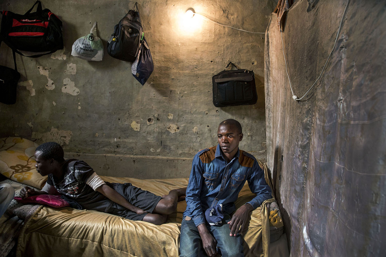 Adam (25 years) from Zambia in a windowless room he shares with four other migrant workers, May 22, 2015.