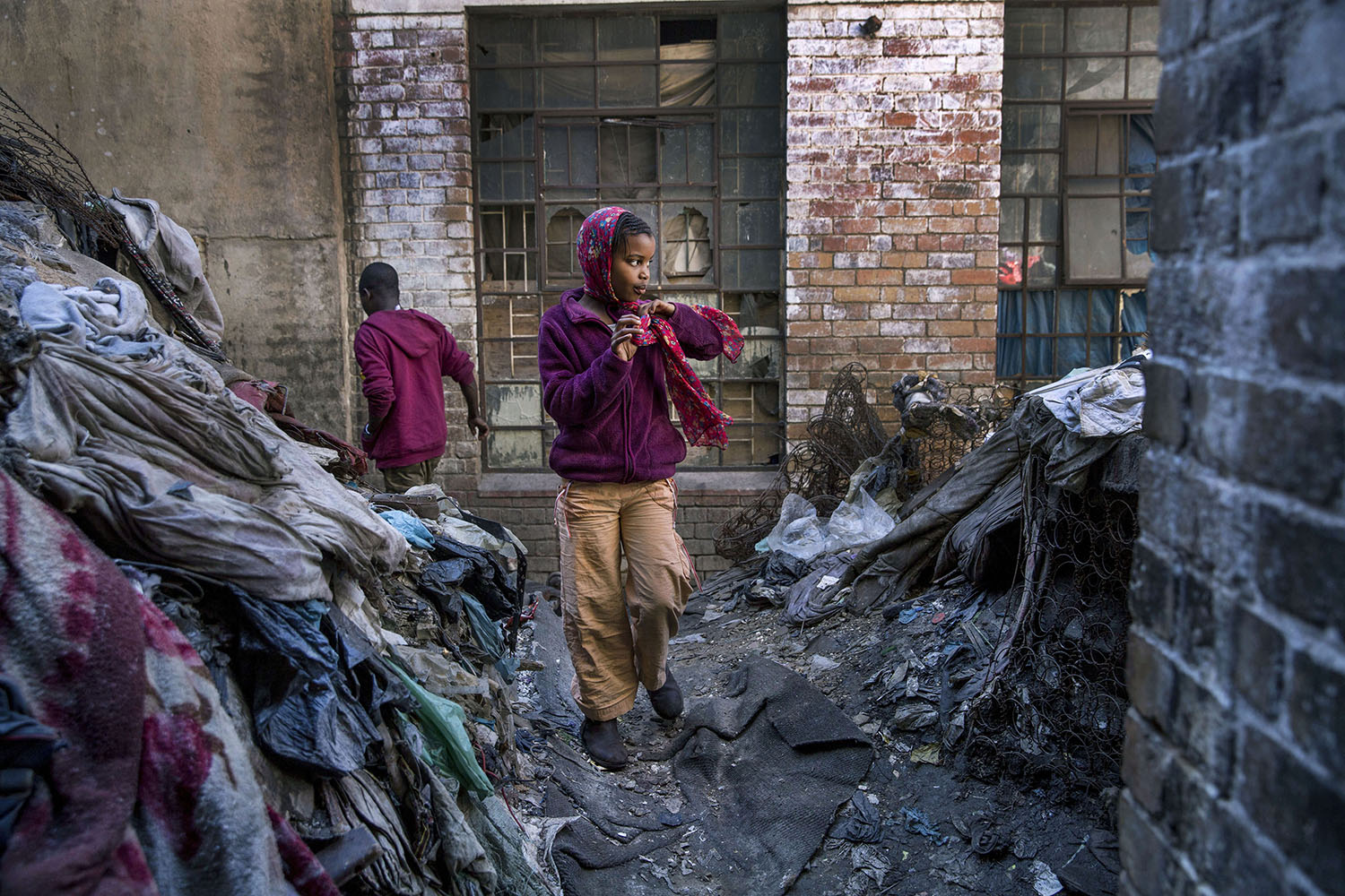 A young girl walks in a rubbish filled courtyard, July 19, 2015.