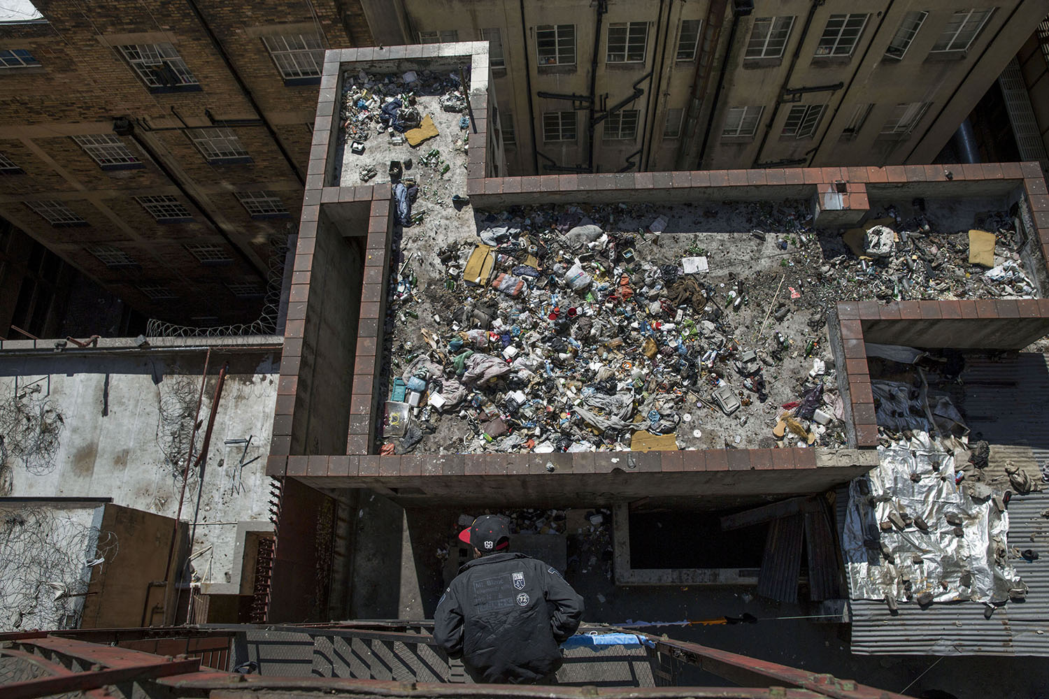 A man looks on to the rubbish filled roof of a derelict building, in the inner city of Johannesburg, Aug. 2, 2015.