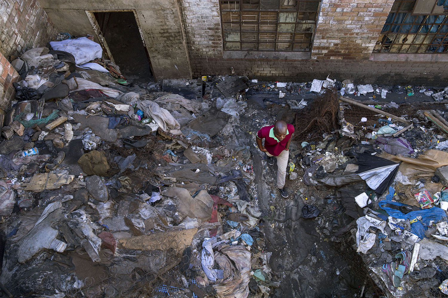 An African migrant resident walking in the rubbish filled courtyard between two derelict buildings, July19, 2015.