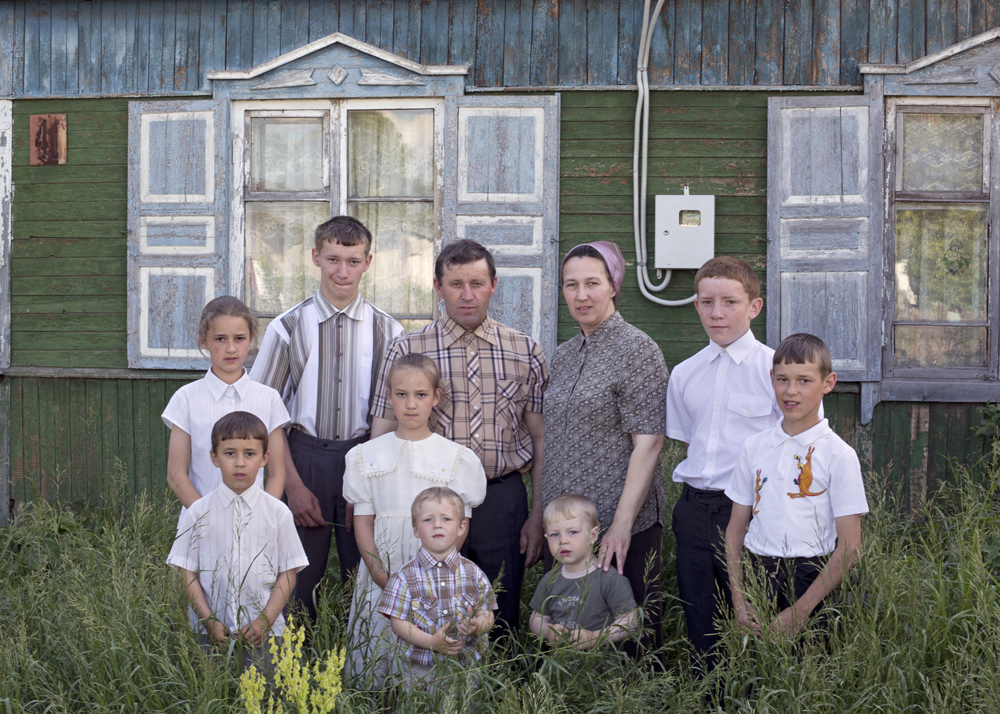 A family of ten stands in front of their old house, which will be ­demolished soon in Petrovka, Omsk Oblast, Russia, 2014.