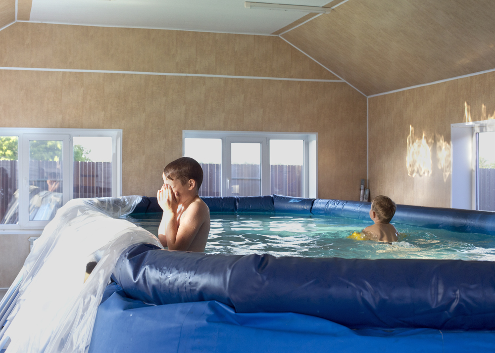 Young boys play in a swimming pool three days after a house purchase in Solnzevka, Russia, 2014.