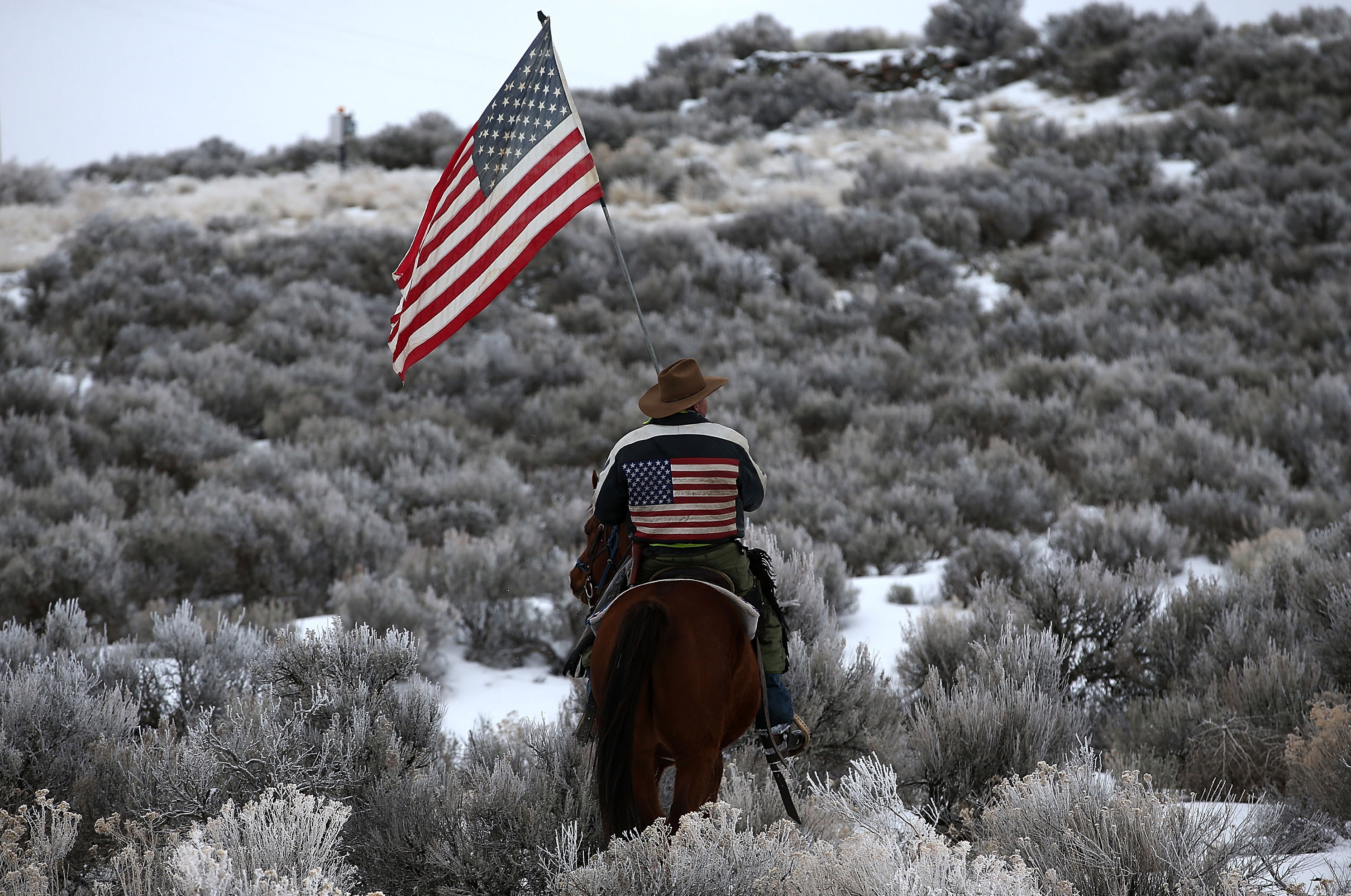 Dwayne Ehmer carries an American flag as he rides his horse on the Malheur National Wildlife Refuge near Burns, Ore., on Jan. 7, 2016. (Justin Sullivan—Getty Images)