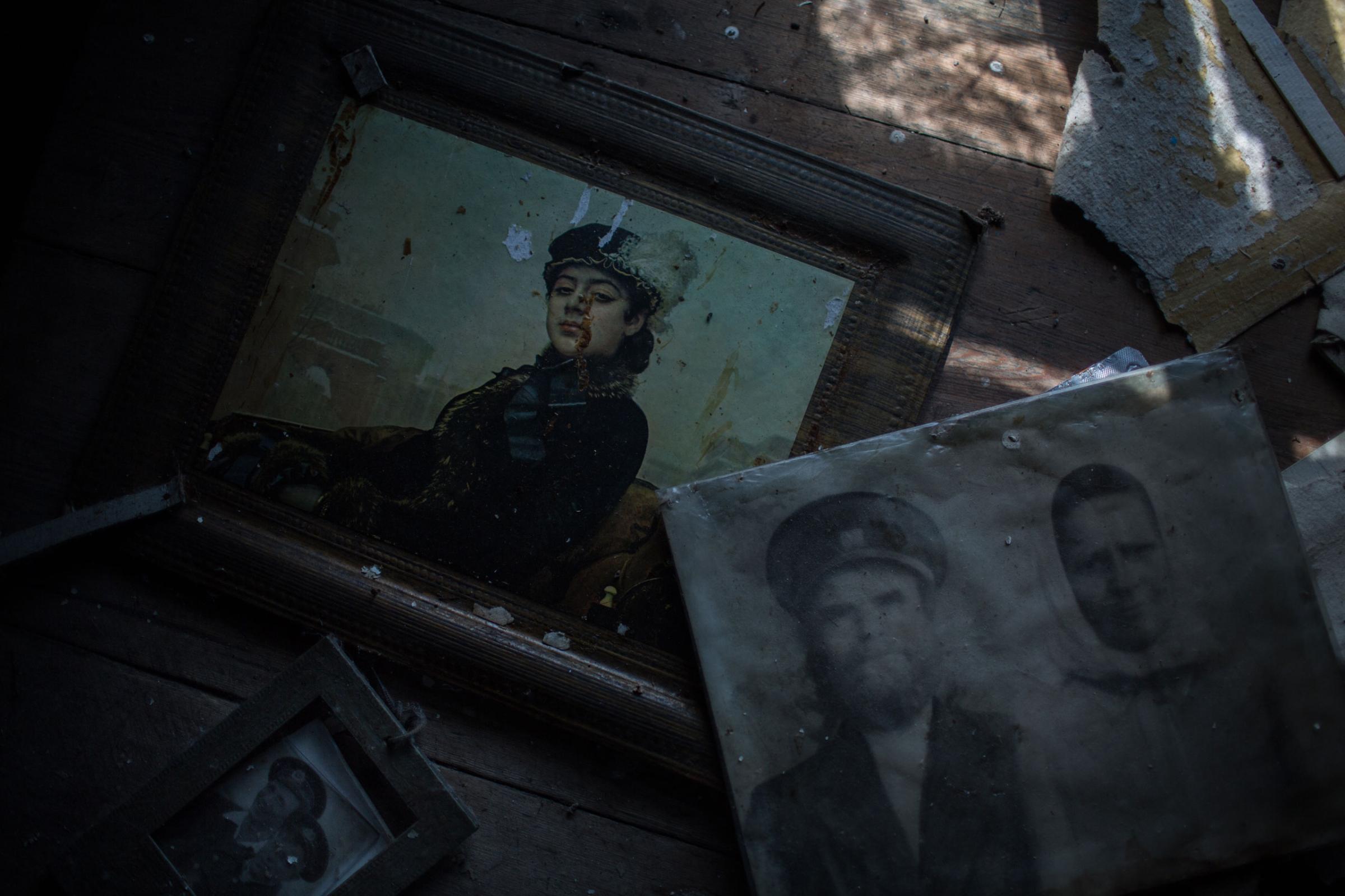 The black-and-white portrait belonged to two people who once lived in a now abandoned house, in the village of Vorobevo. Beneath, a reproduction of Ivan Kramskoy's "The Unknown Woman" is seen.
