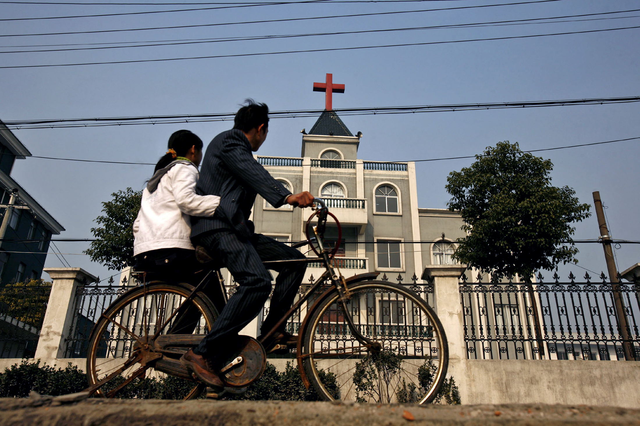 A local resident rides a bicycle past a church in Xiaoshan