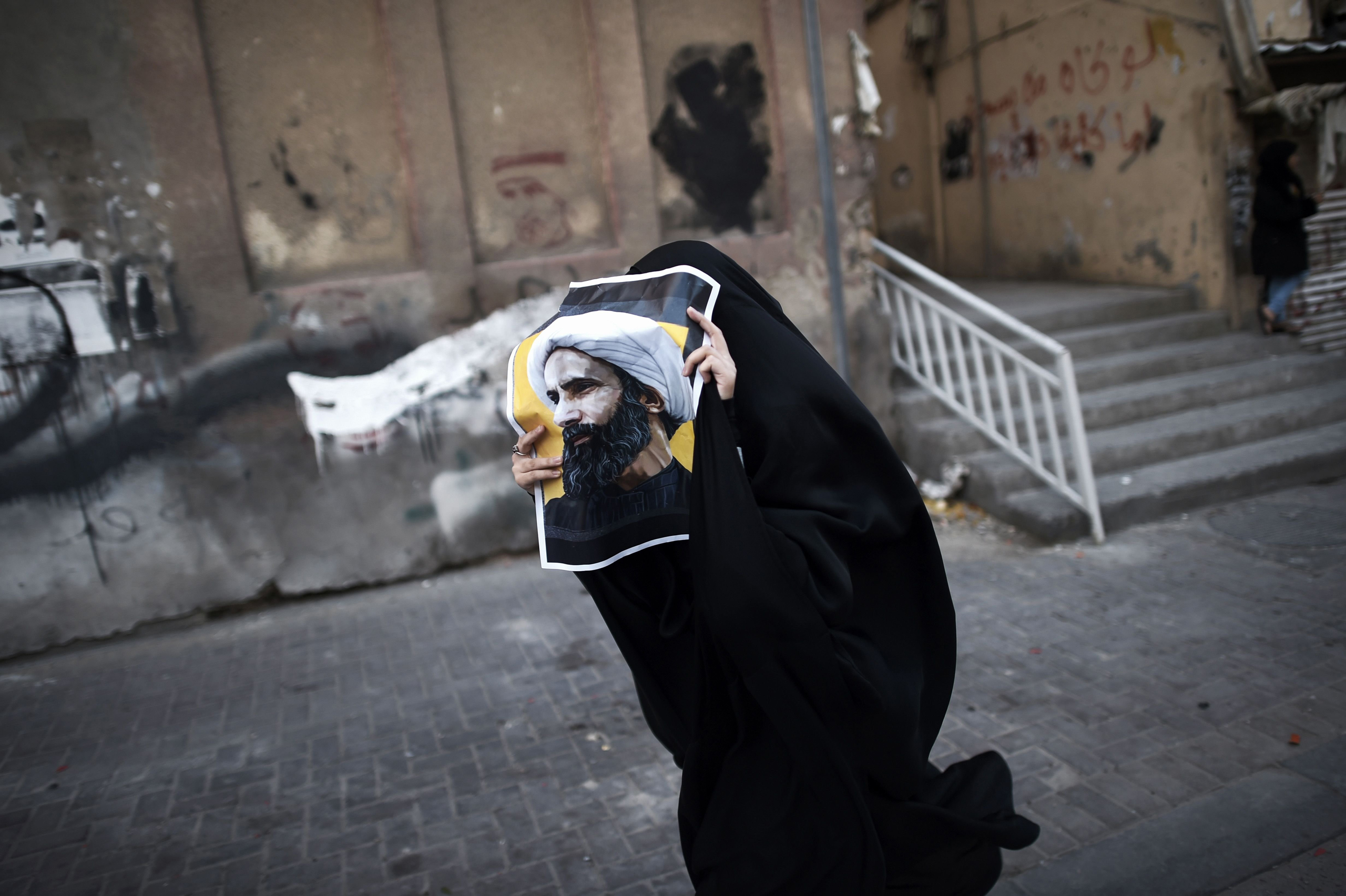 A Bahraini protester holds a poster of Shi‘ite cleric Nimr al-Nimr, who was executed by Saudi Arabia (Mohammed Al-Shaikh)