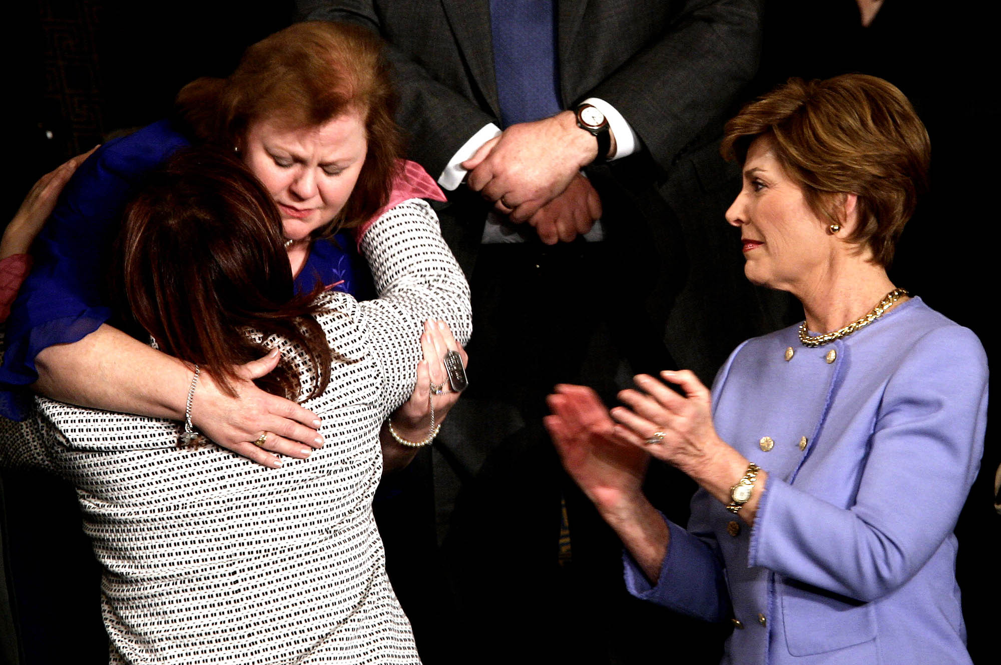 First lady Laura Bush, right, applauds as Safia Taleb al-Suhail, leader of the Iraqi Women's Political Council, back to camera, hugs Janet Norwood of Pflugerville, Texas, on Capitol Hill, Feb. 2, 2005. Norwood's son, Sgt. Byron Norwood, was killed in Iraq in Nov. 2004.