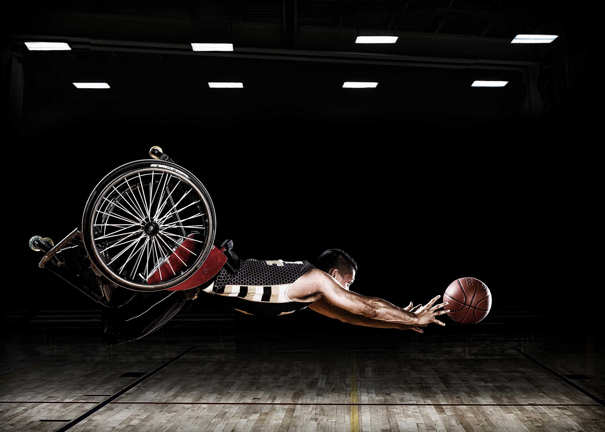 A RIC Hornets wheelchair basketball team member reaches for a basketball. These images were created for the Rehabilitation Institute of Chicago's Adaptive Sports Program.