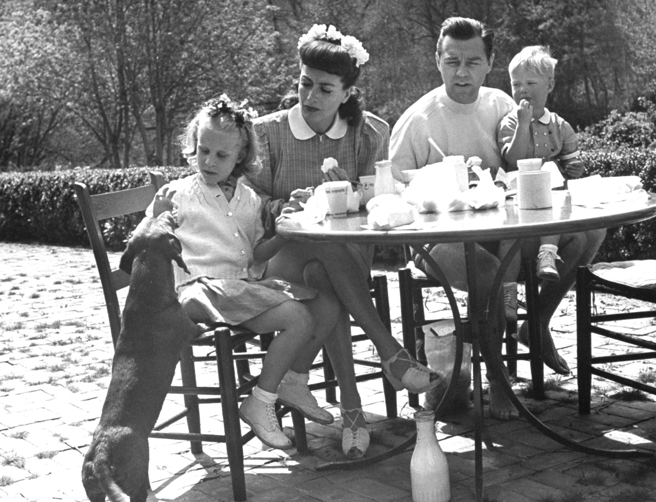 Joan Crawford and her husband, Philip Terry, having a picnic with their adopted children and dog. 1945.