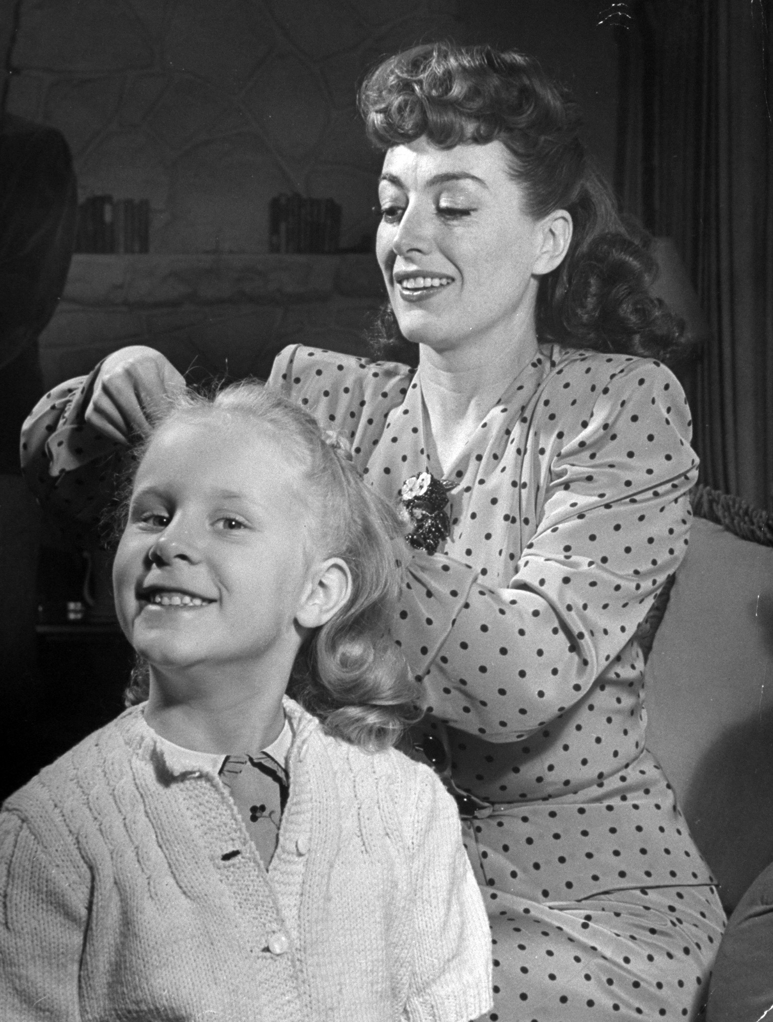 Joan Crawford fixing her adopted daughter Christina Crawford's hair, with the 5-year-old smiling proudly. 1945.