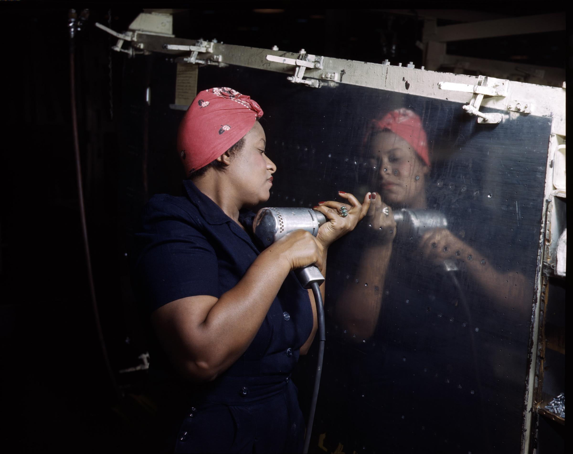 Operating a hand drill at Vultee-Nashville, woman is working on a "Vengeance" dive bomber, Tennessee, February 1943. Photographed by Alfred T. Palmer for the Farm Security Administration.