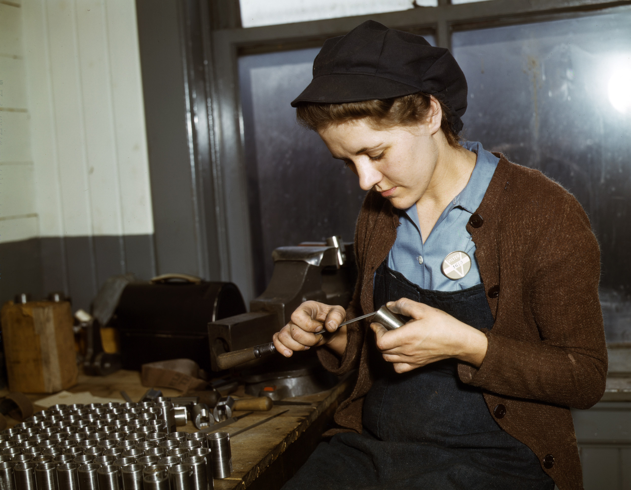 War production workers at the Vilter [Manufacturing] Company making M5 and M7 guns for the U.S. Army, Milwaukee, Wis. Ex-housewife, age 24, filing small parts. Her husband and brother are in the armed service. February 1943. Photographed by Howard R. Hollem for the Farm Security Administration.