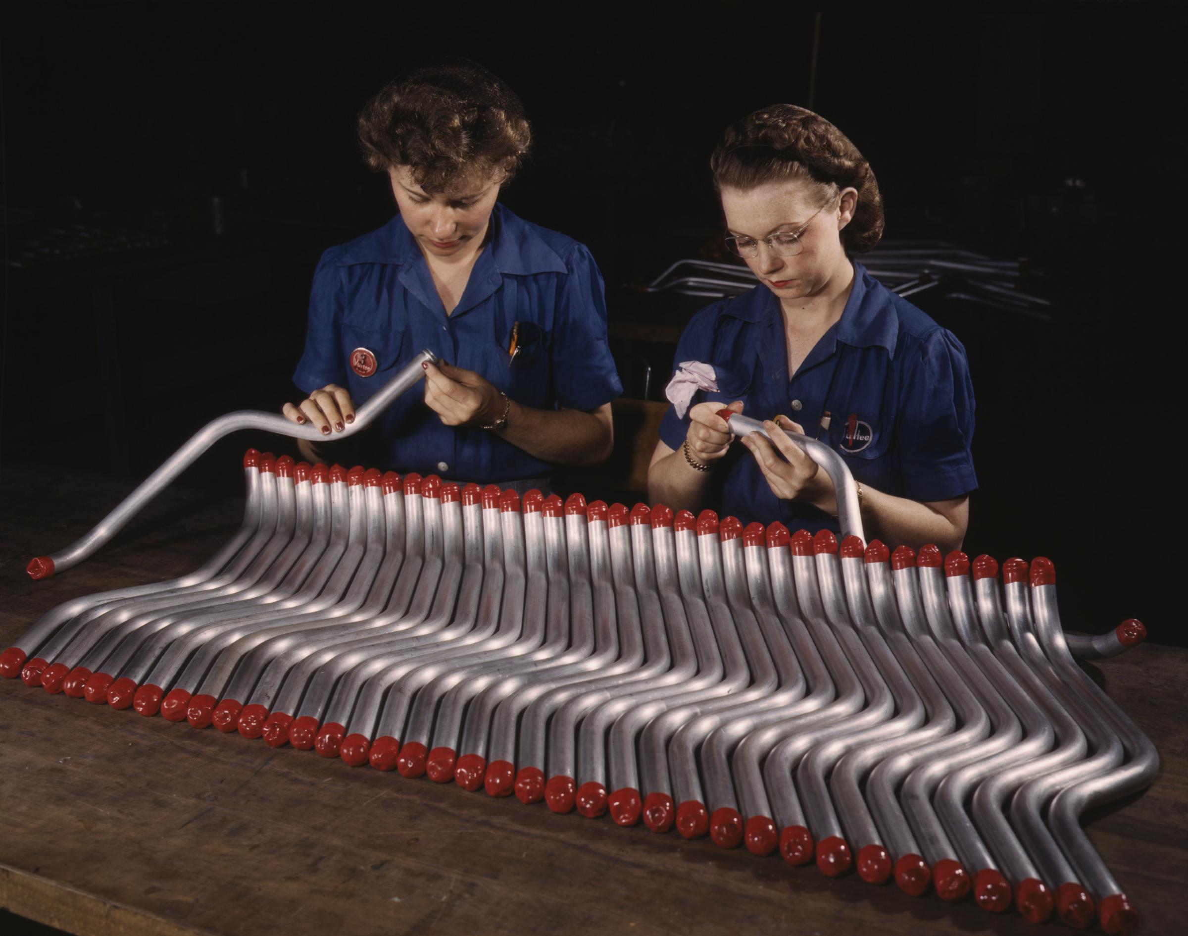 Two women workers are shown capping and inspecting tubing which goes into the manufacture of the "Vengeance" (A-31) dive bomber made at Vultee's Nashville division, Tennessee, February 1943. Photographed by Alfred T. Palmer for the Farm Security Administration.